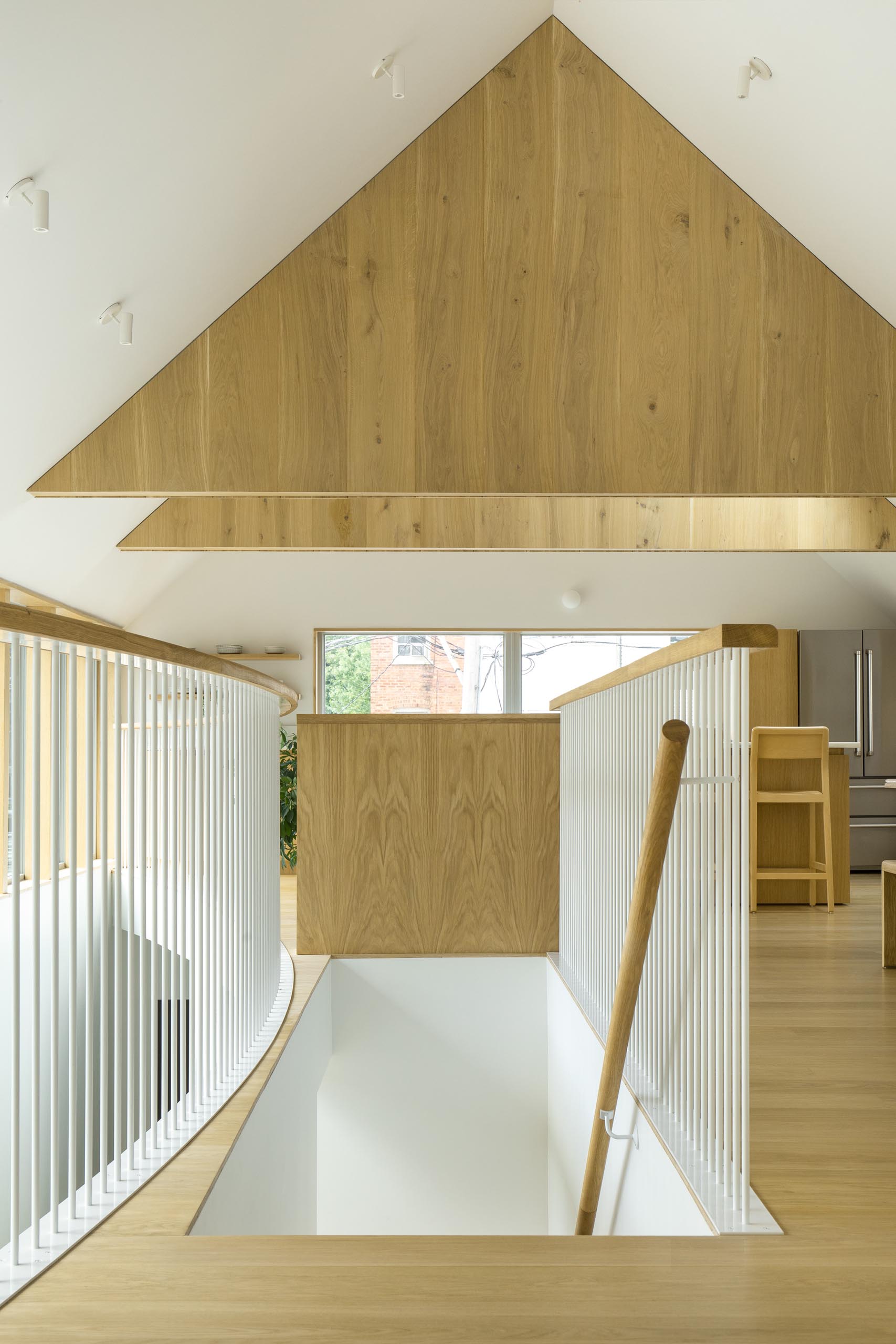 Wood stairs with a matching handrail lead up to the social areas of this modern home.