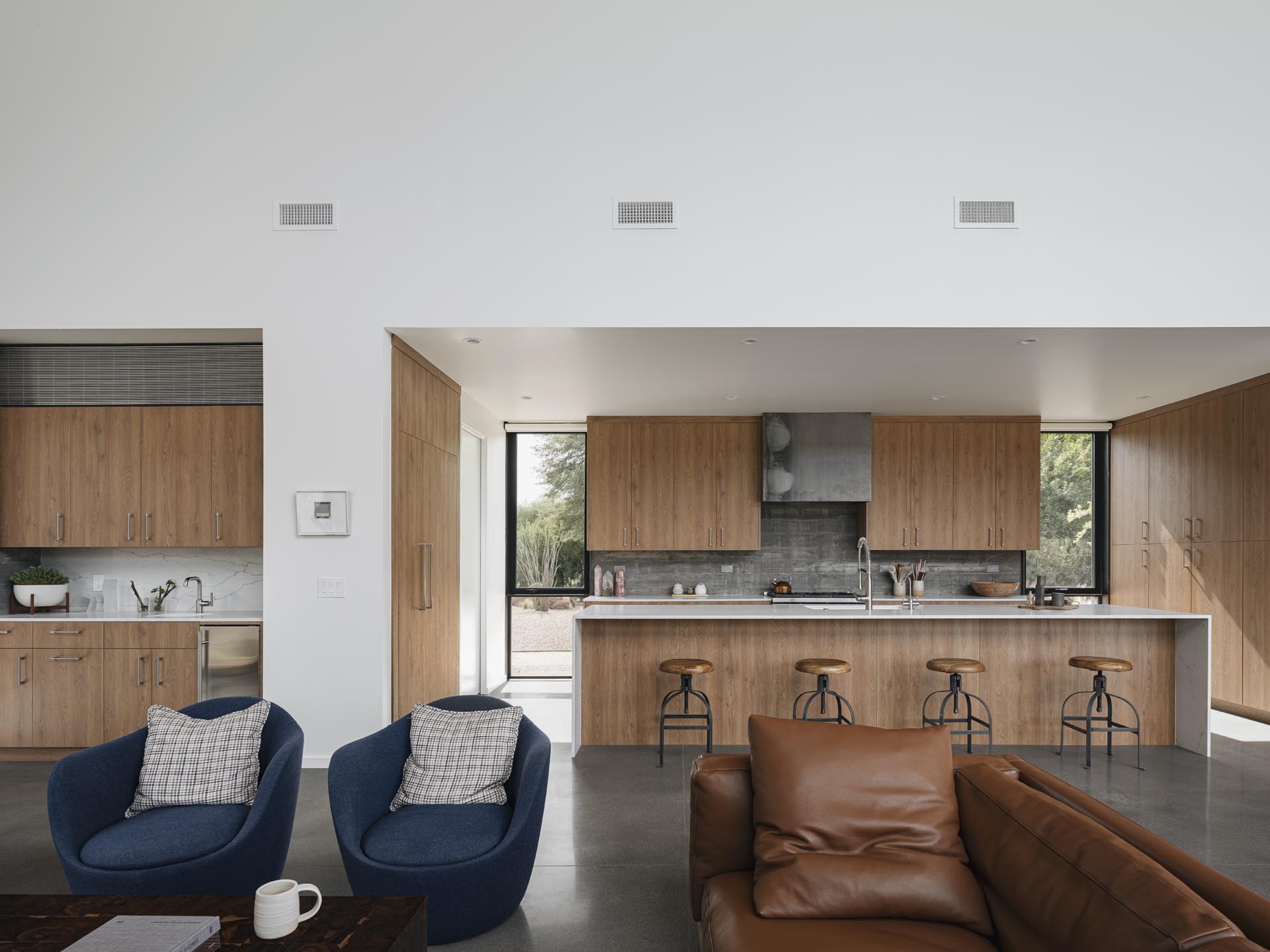 The wood cabinetry in the kitchen has been installed right up against the board-formed concrete wall, while a long kitchen island creates plenty of counter space.