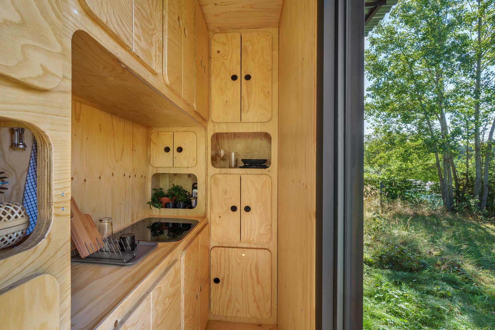 A plywood kitchen inside a tiny home made from a small shipping container.