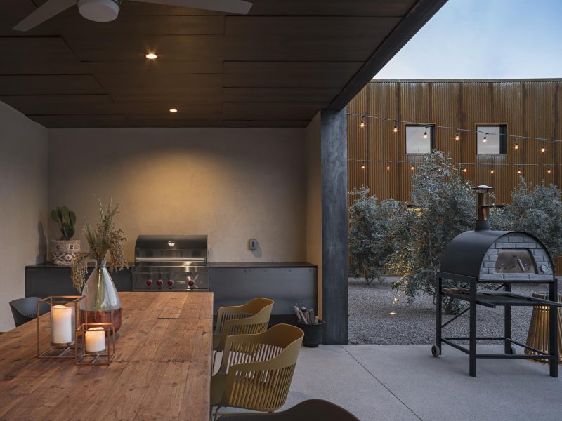 A modern outdoor kitchen with a covered dining area.