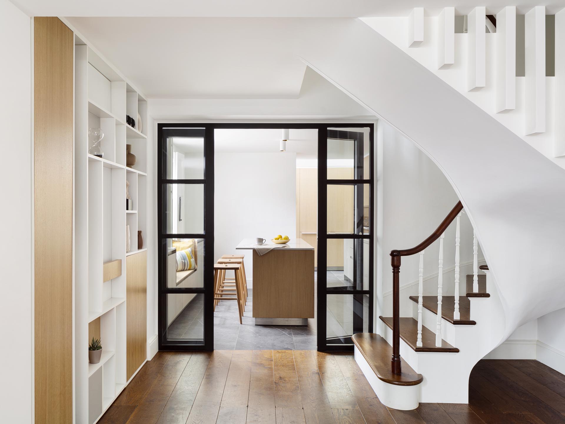 An updated early Victorian townhome interior with black framed glass doors.