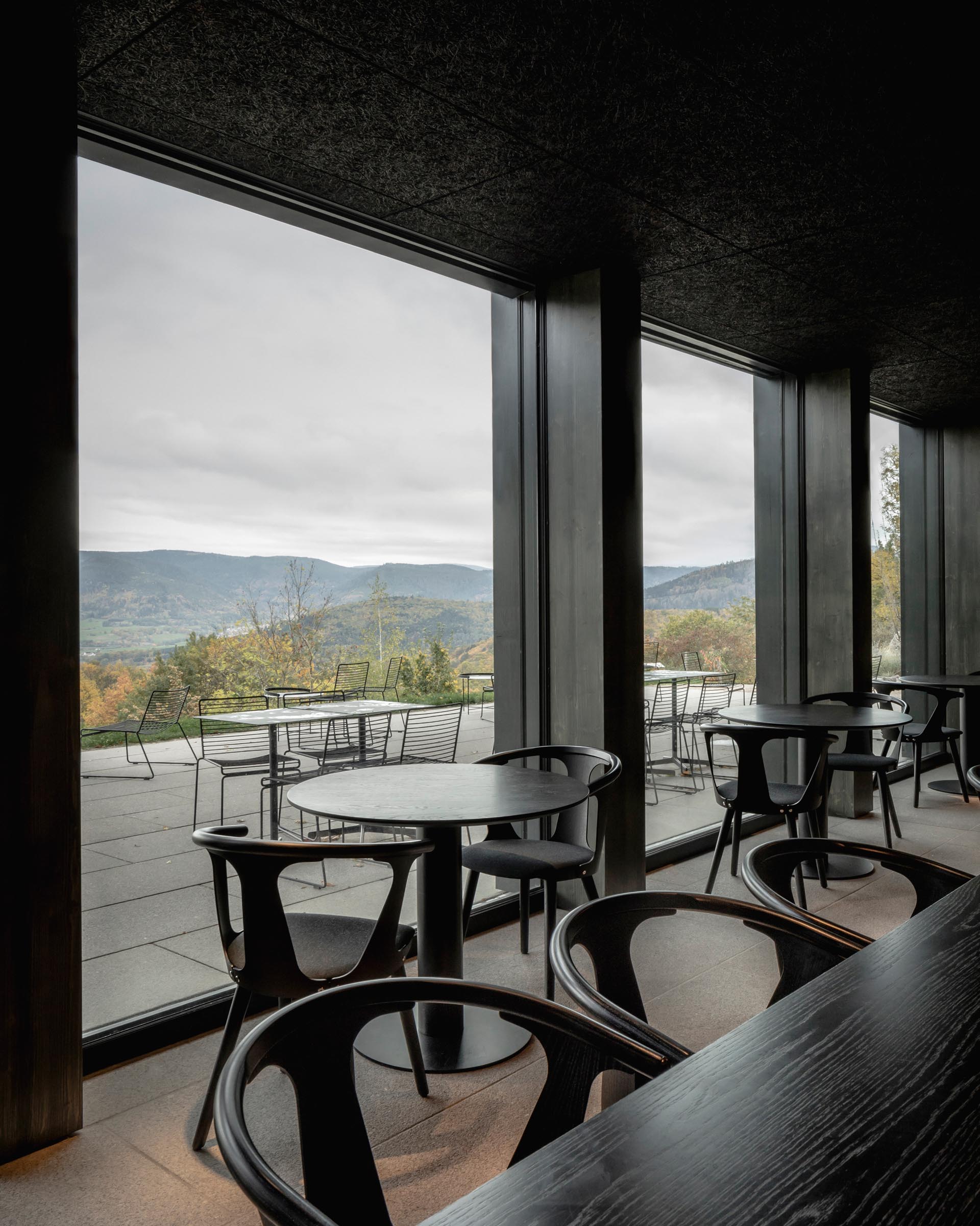 A modern hotel restaurant with dark wood accents and large windows.