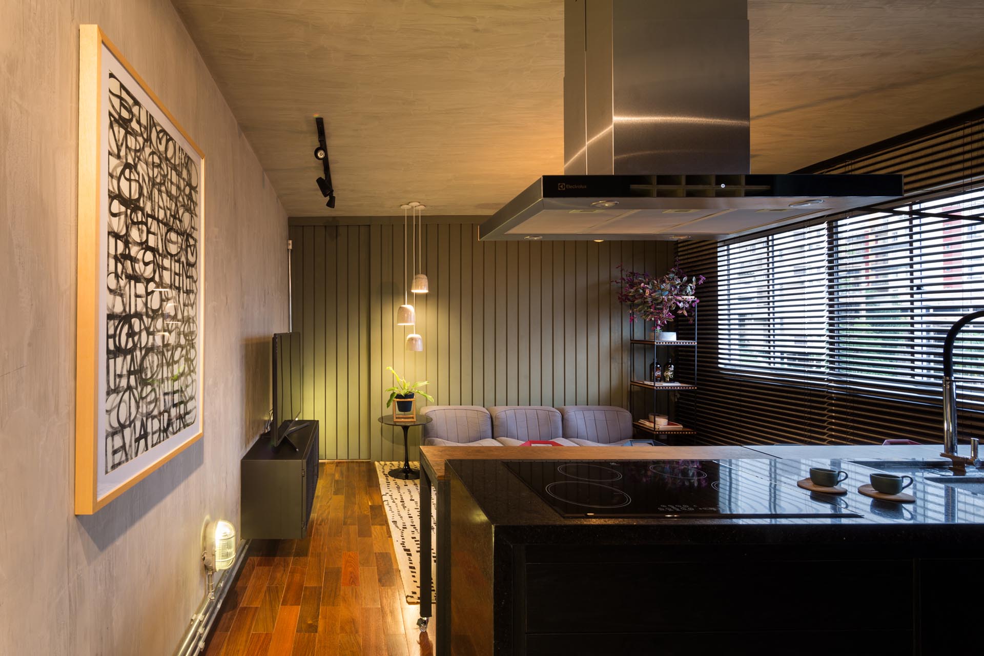 A modern living room in a small apartment with a muted green accent wall made from panels of MDF.