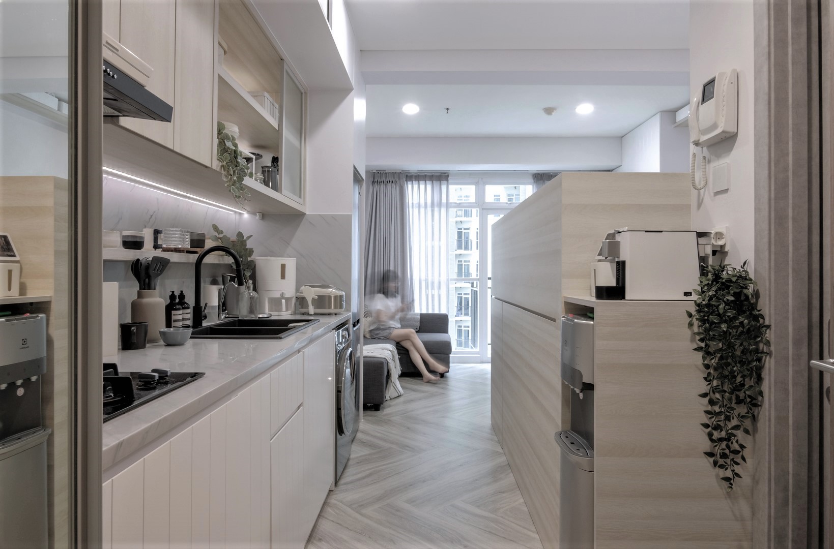 A small remodeled micro apartment that includes a full kitchen, a loft bed, and a bathroom.