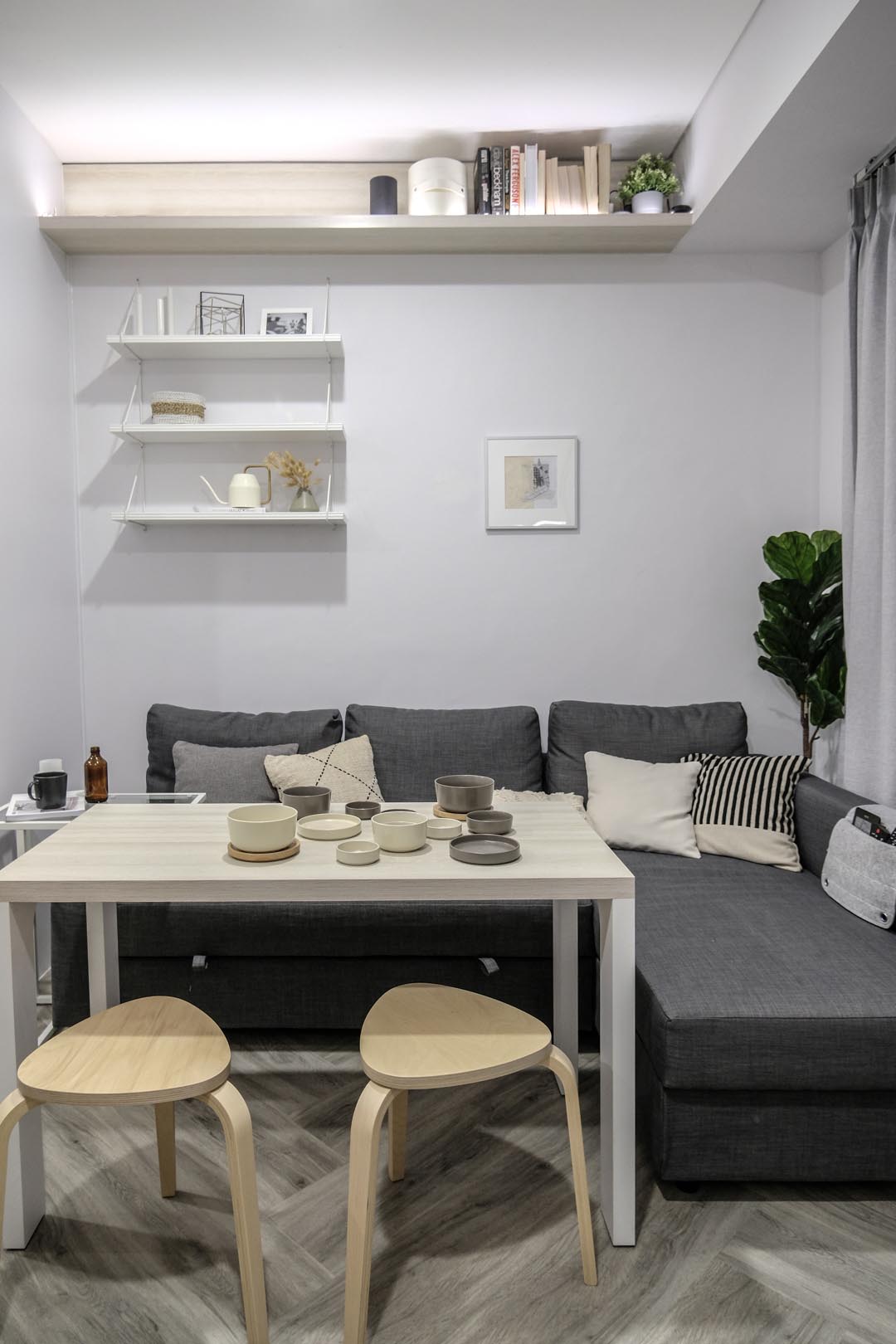 The living room of a small apartment that includes a moveable dining table, and high shelves.