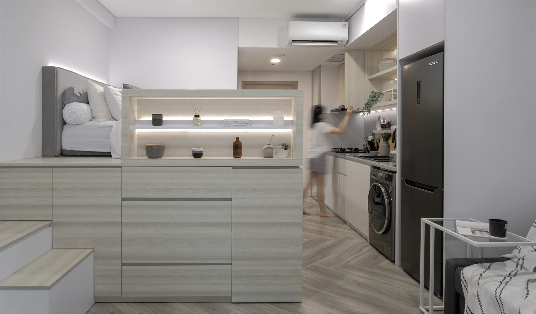 In this micro apartment, the queen-sized loft bed includes storage underneath, and complements the interior palette of white, grey, and wood, chosen to create a tranquil atmosphere.