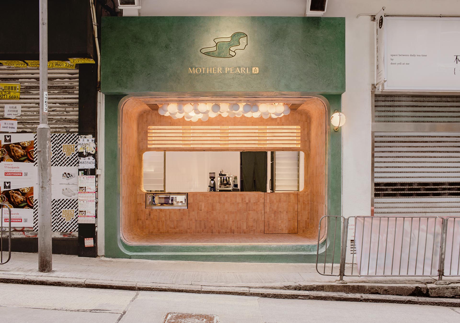 A modern bubble tea house with an olive green facade and a earth colored tiled interior.