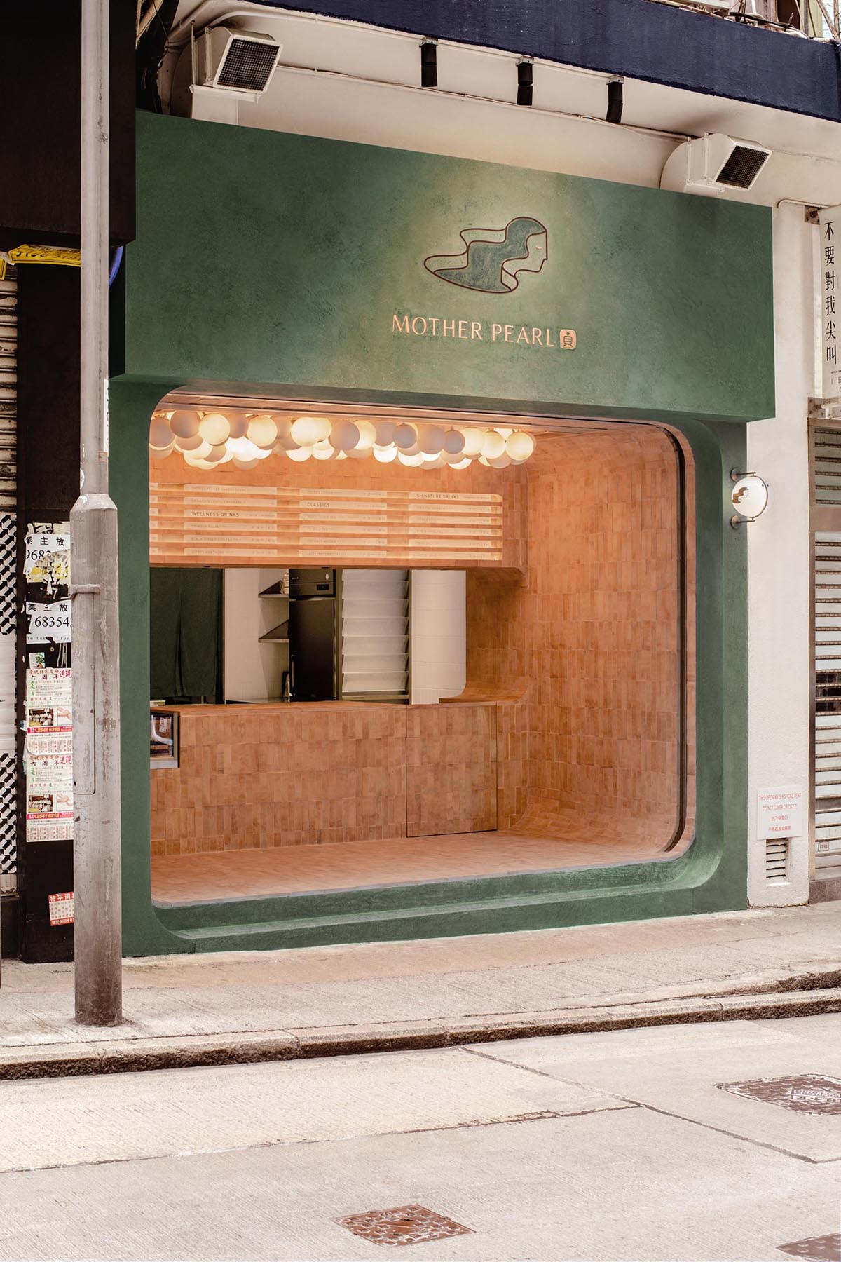 A modern bubble tea house with an olive green facade and a earth colored tiled interior.