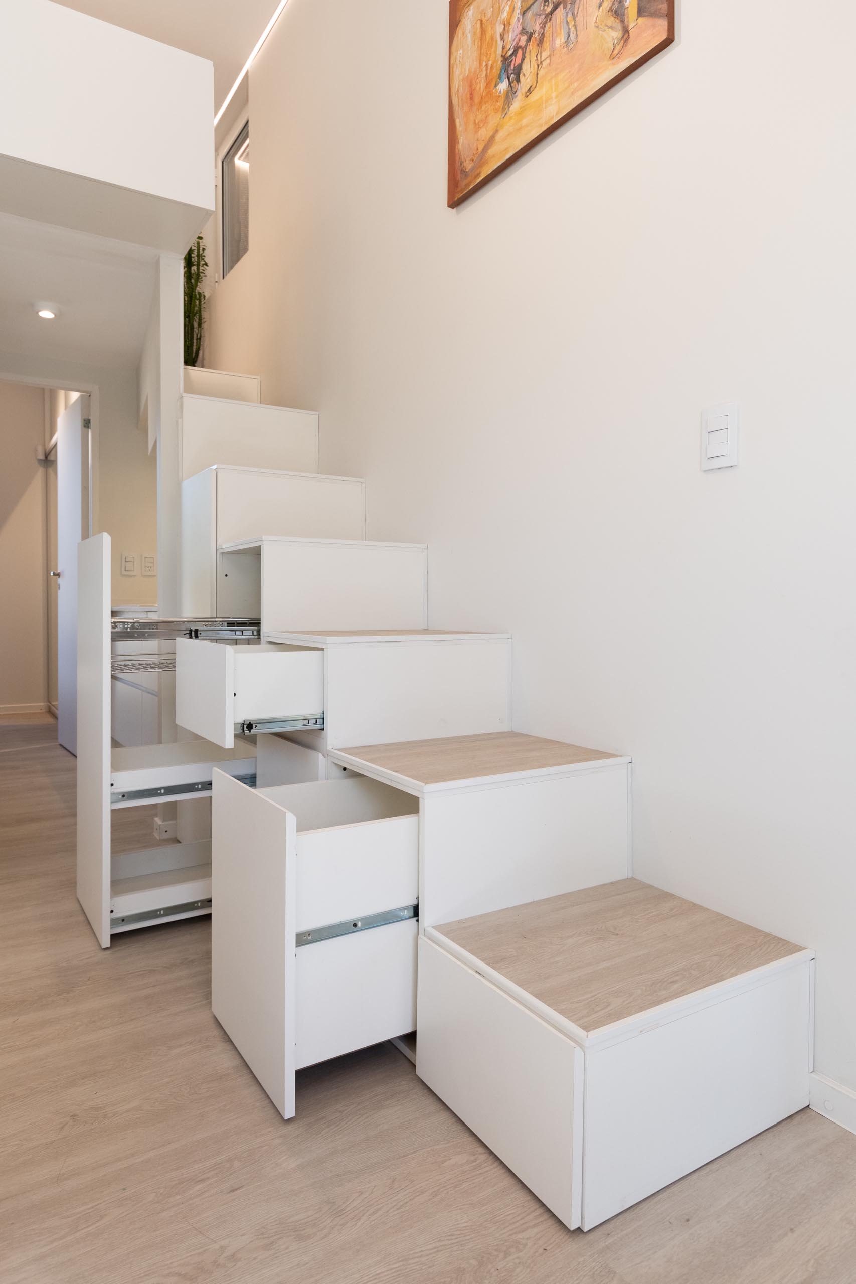 A modern home with a staircase that includes storage and leads to a mezzanine level.