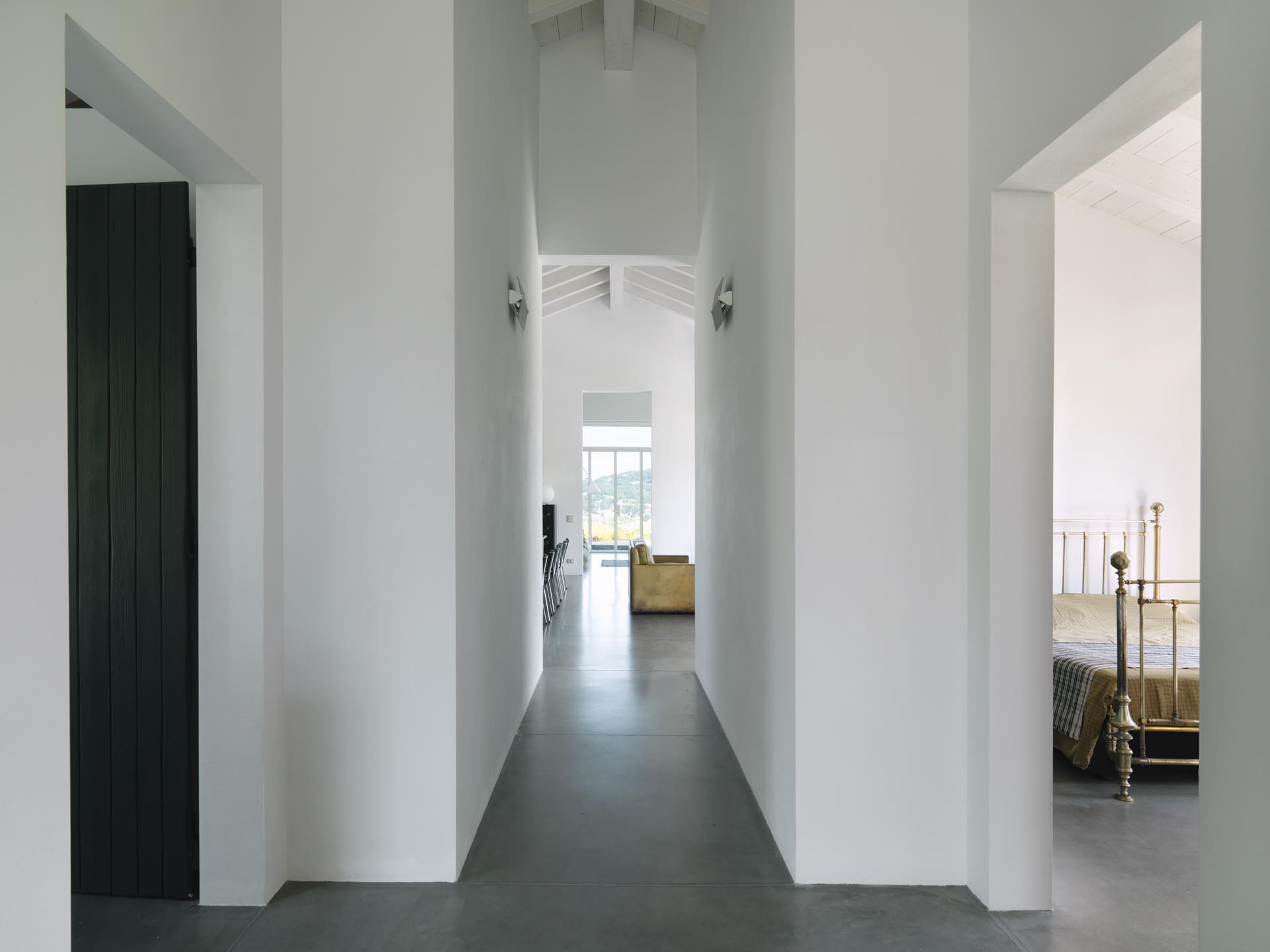 A modern farmhouse hallway with white lime tempera walls and concrete floors.