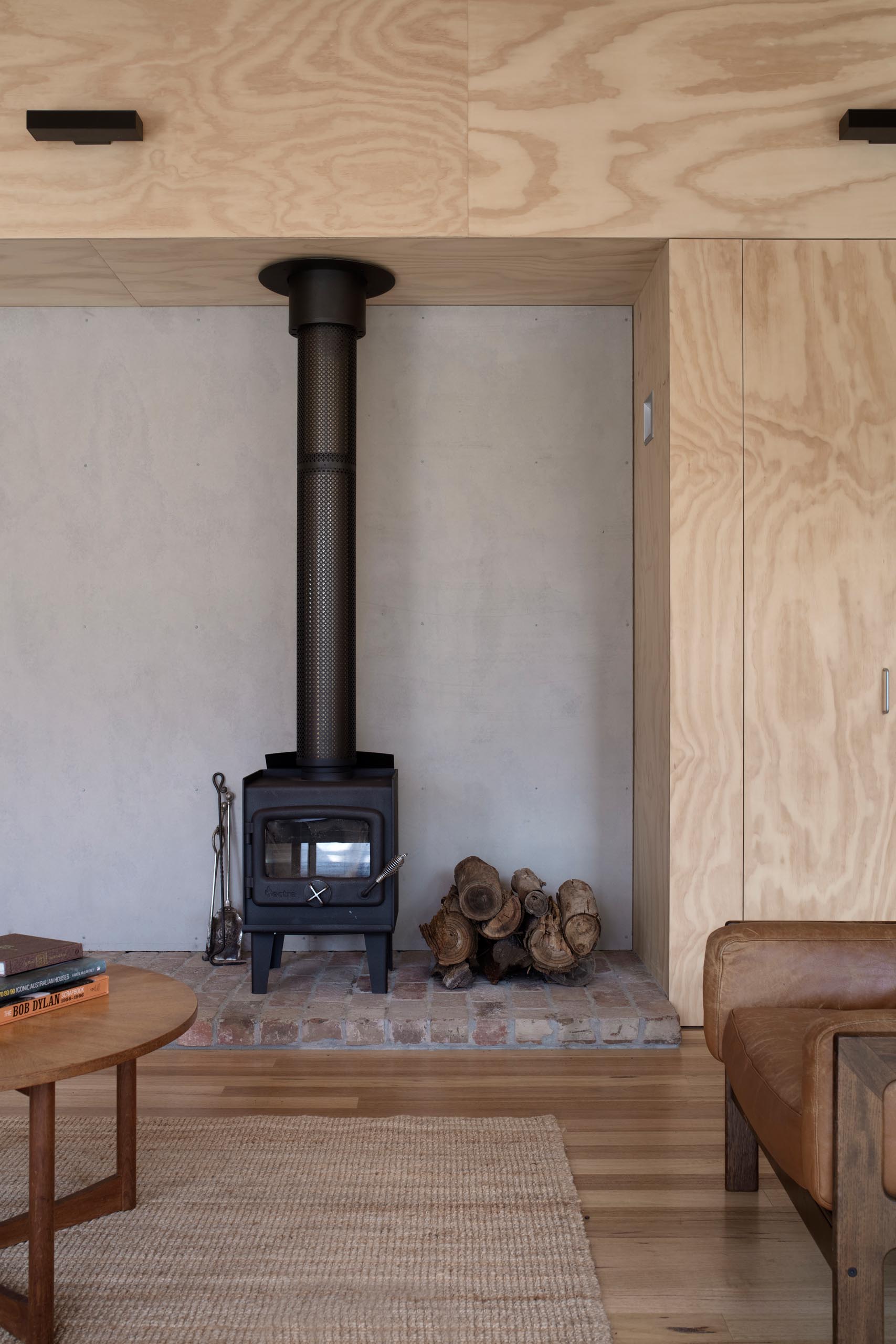 Salvaged bricks were reused in the hearth of this fireplace, which has a matte black finish to match the ceiling fan.