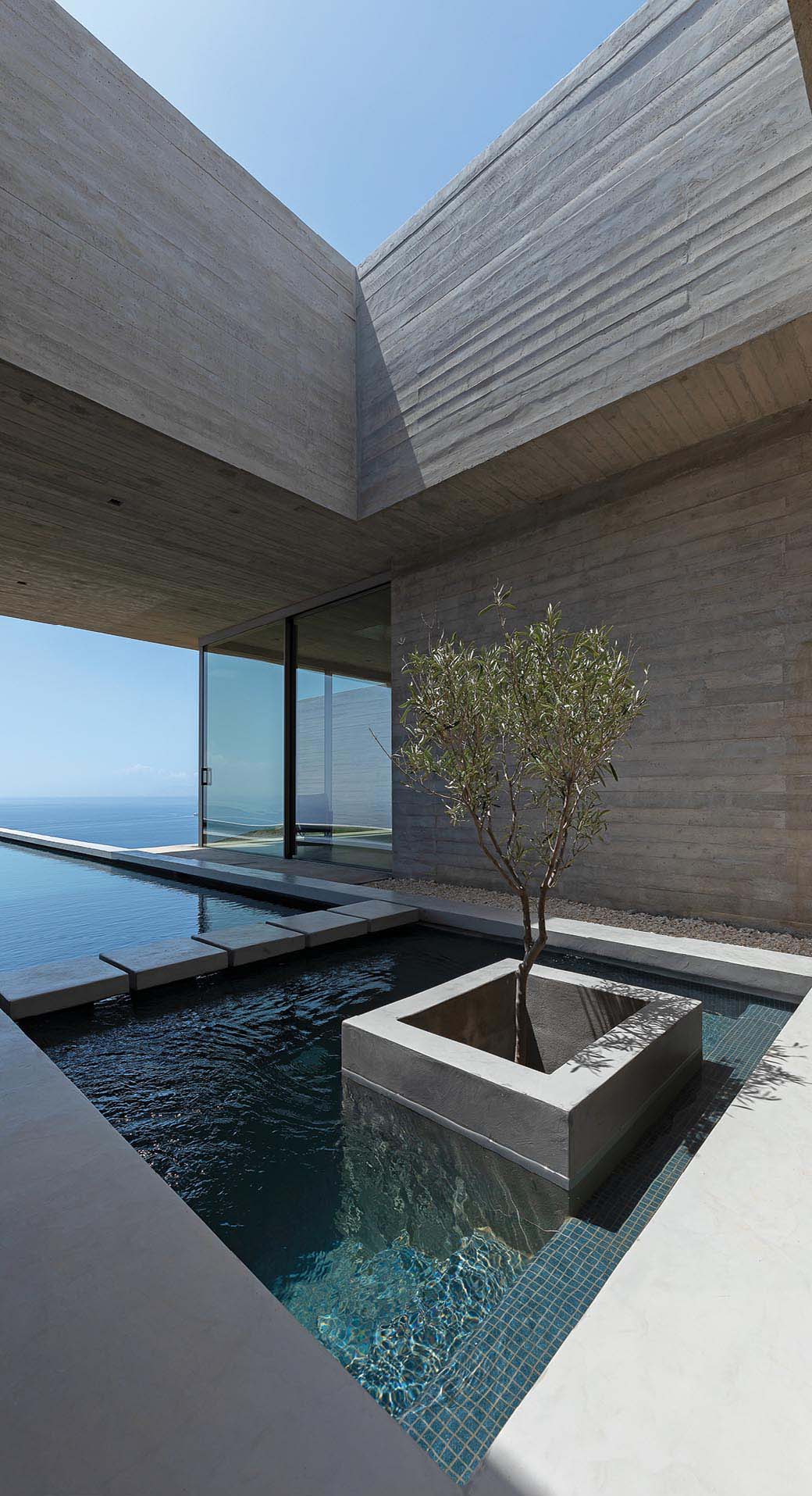 A modern concrete house with a linear swimming pool.