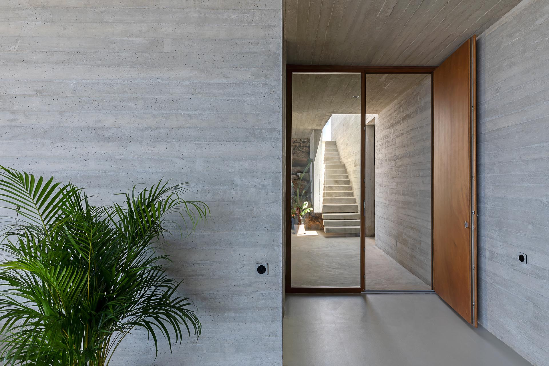 A modern concrete home with a large wood front door.