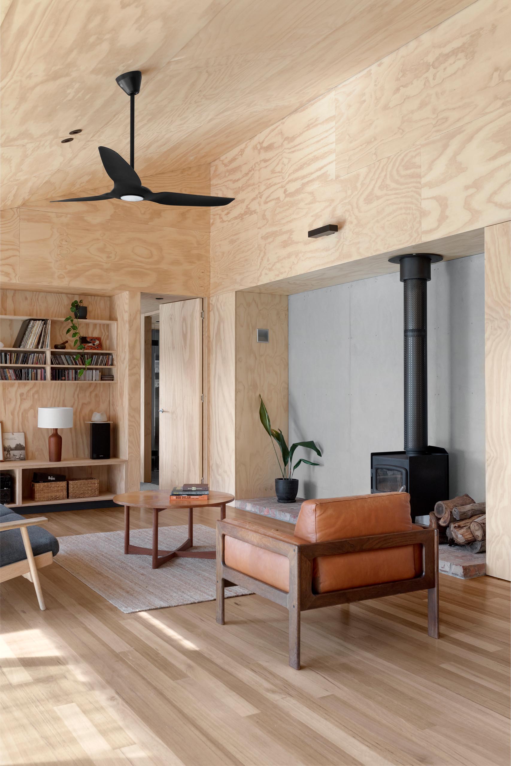 Salvaged bricks were reused in the hearth of this fireplace, which has a matte black finish to match the ceiling fan.