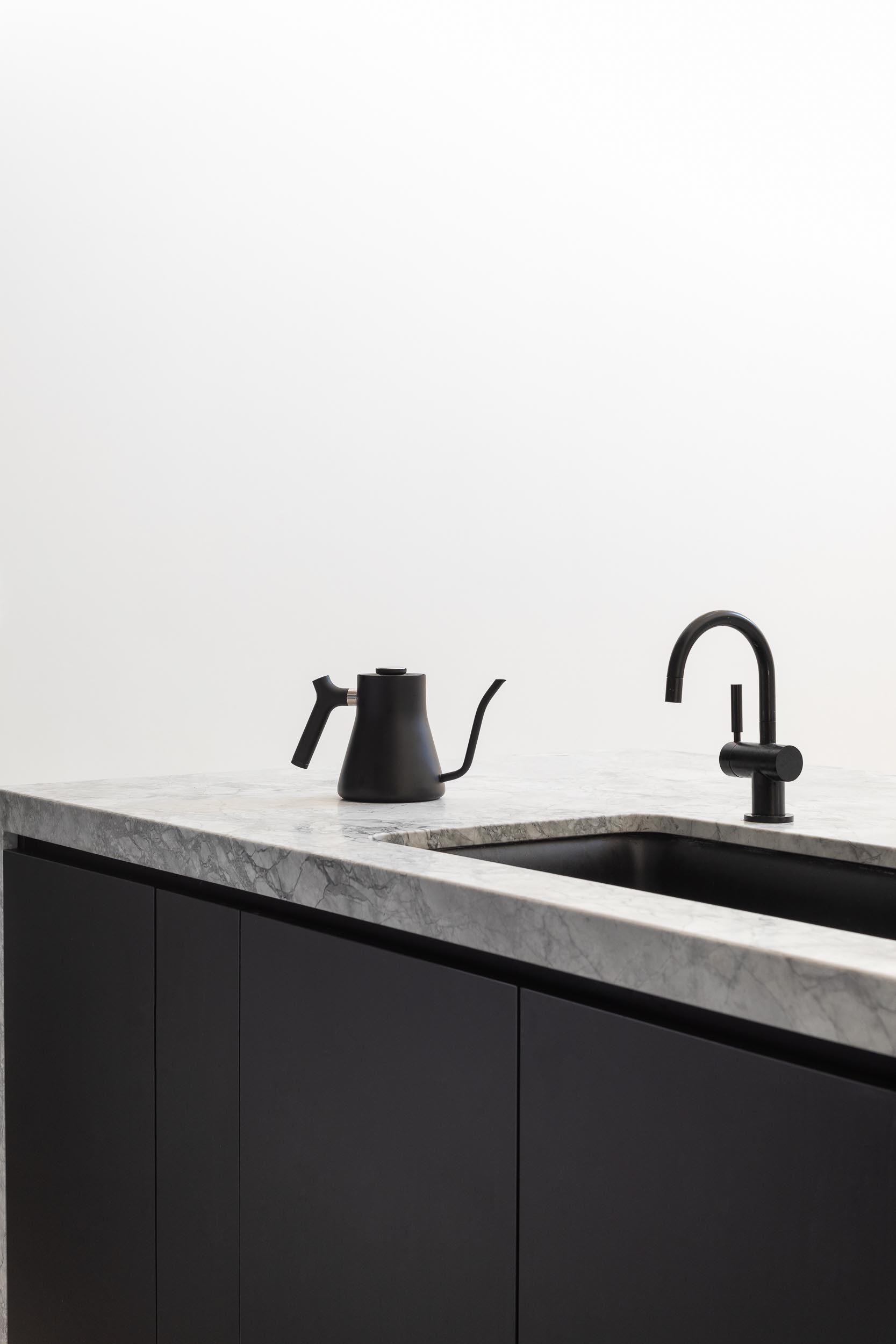 A modern kitchen island with matte black cabinets, and a matching matte black sink and faucet.