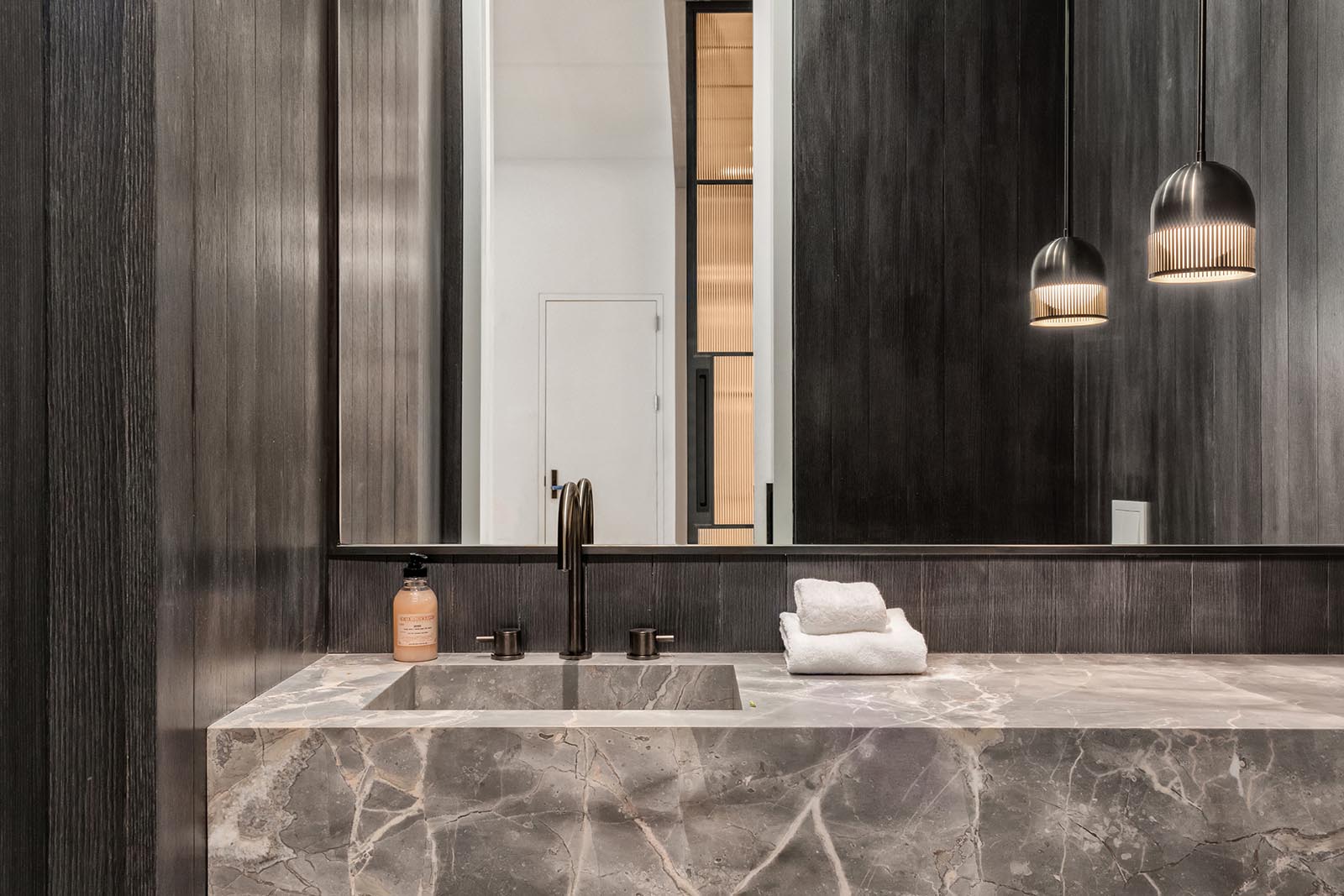 In this modern bathroom, dark wood walls have been used to create a dramatic appearance.