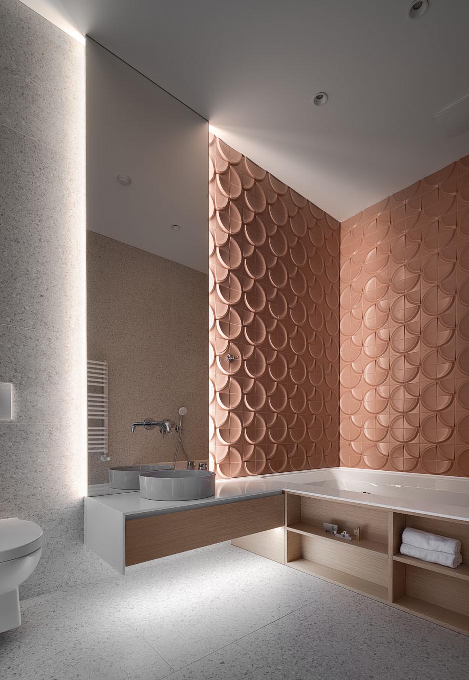 In this modern bathroom, 3-dimensional wall tiles create a unique textured look that's accentuated by the lighting coming from the backlit mirror.