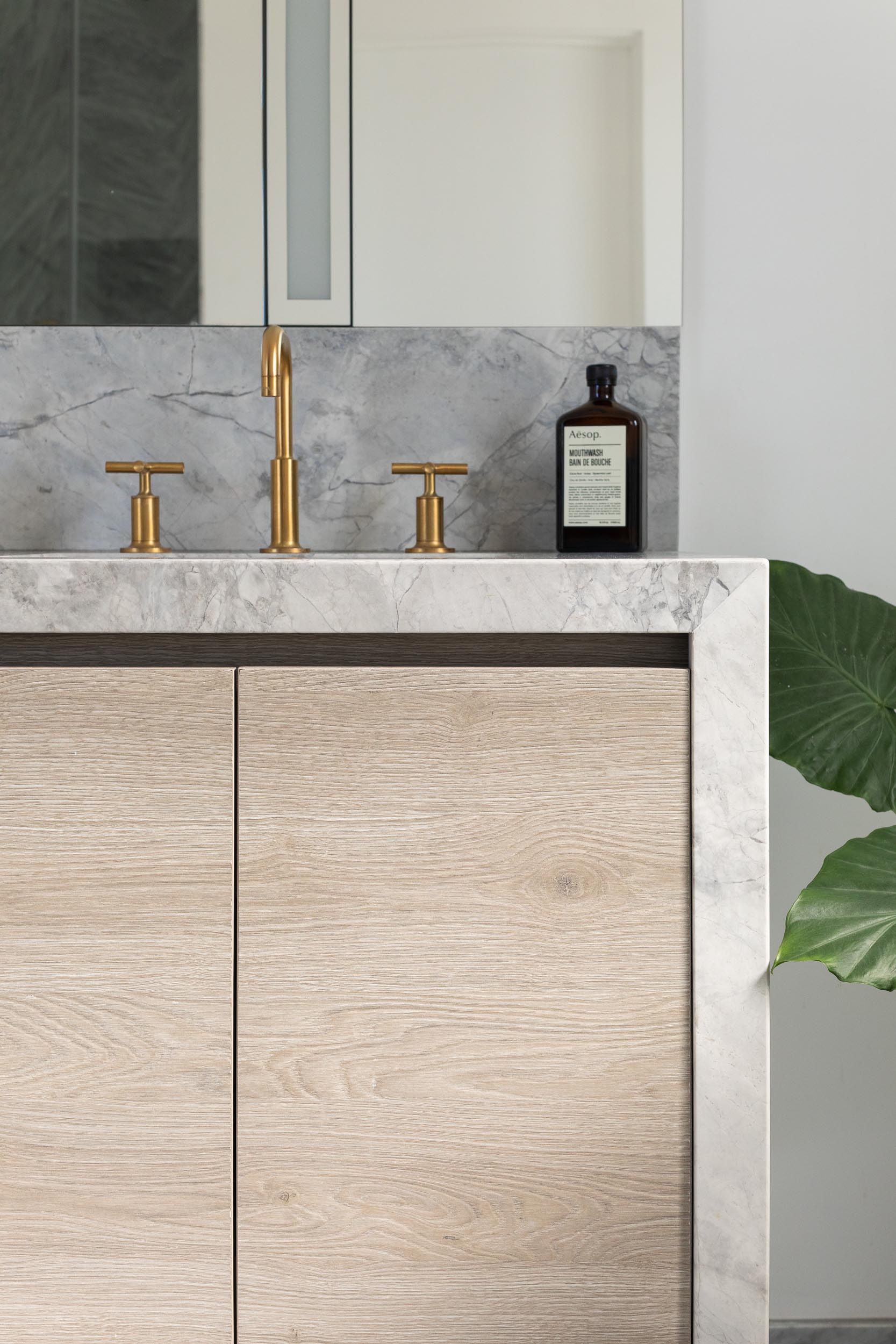 In this modern en-suite bathroom, there's a freestanding white bathtub, a walk-in shower, and a wood vanity with a waterfall countertop.