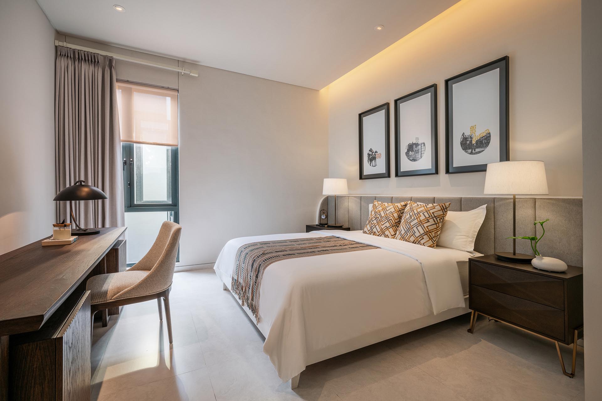 A modern bedroom with a neutral color palette, and a headboard that lines the entire width of the wall.