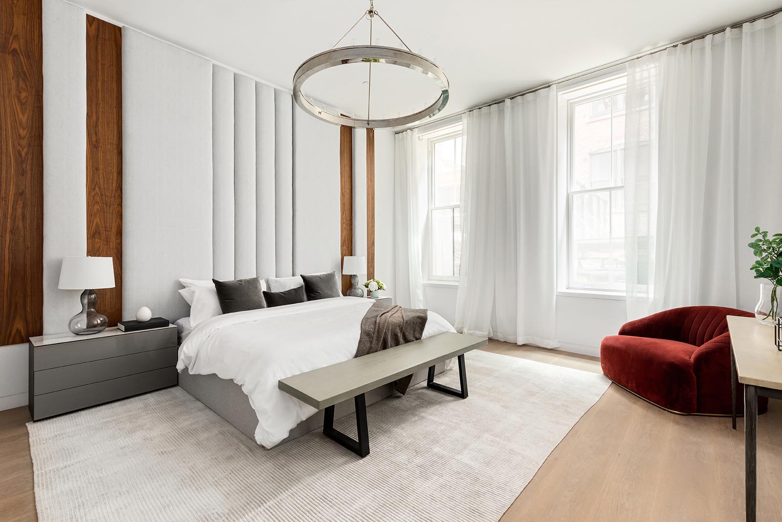 This modern master suite includes a custom wood and upholstered panel headboard that draws the eye upwards to the ceiling, making the room feel even larger than it is.