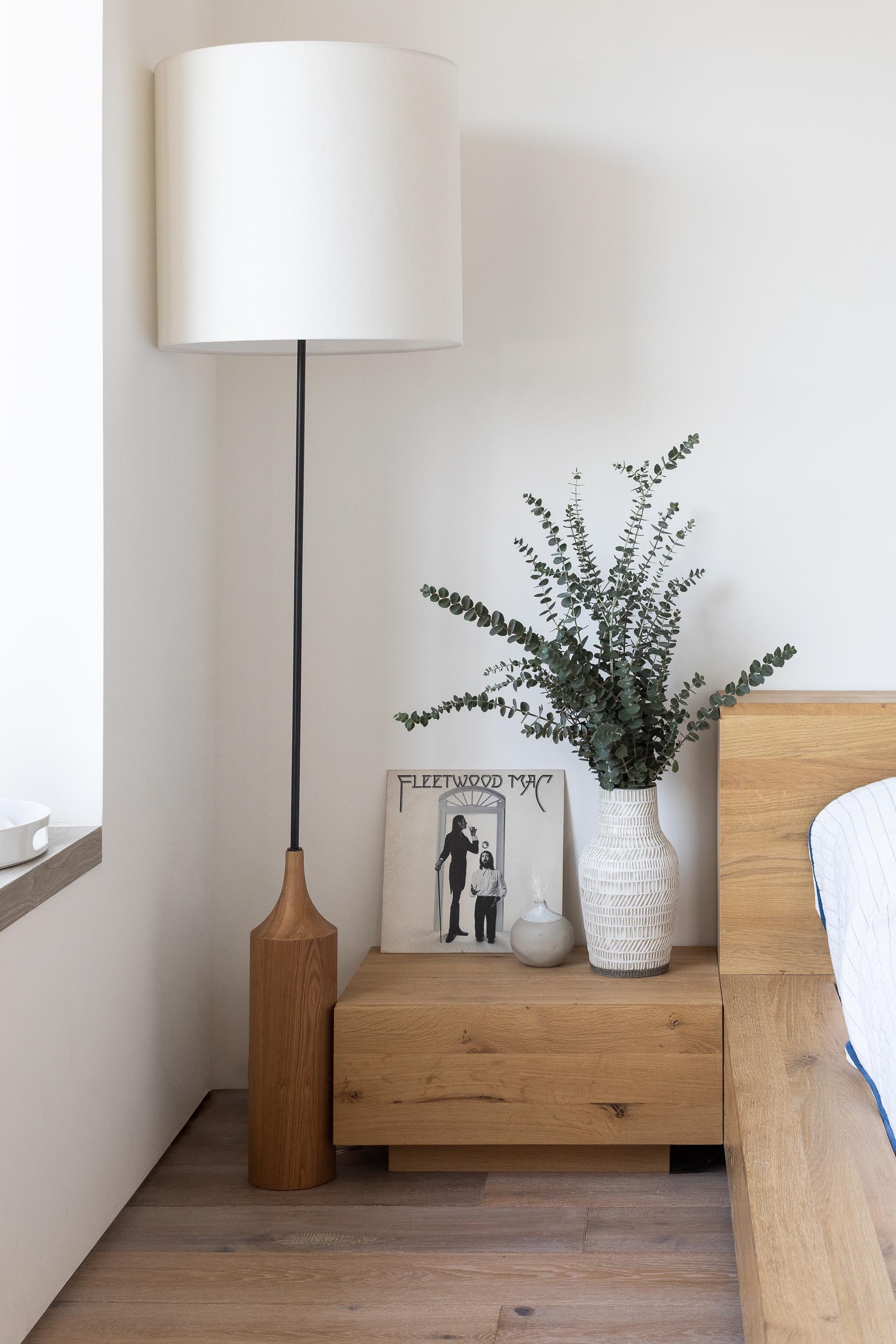 A modern bedroom with a wood bed frame and chunky wood side tables.