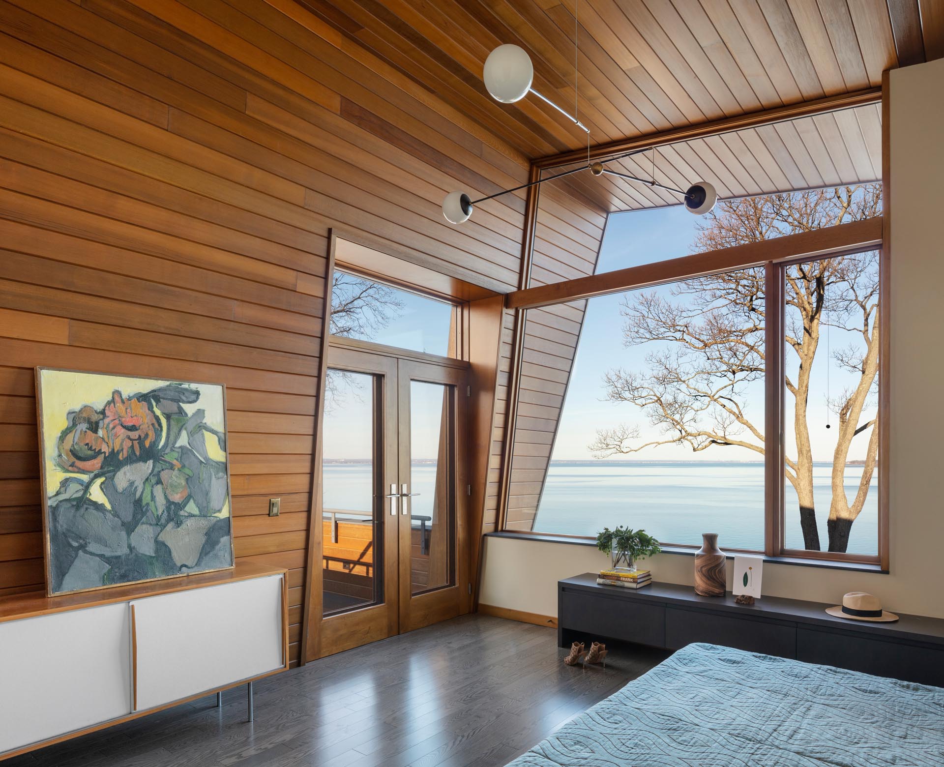 In this modern bedroom, there's a cedar wall that wraps onto the ceiling and travels through to the outdoors.