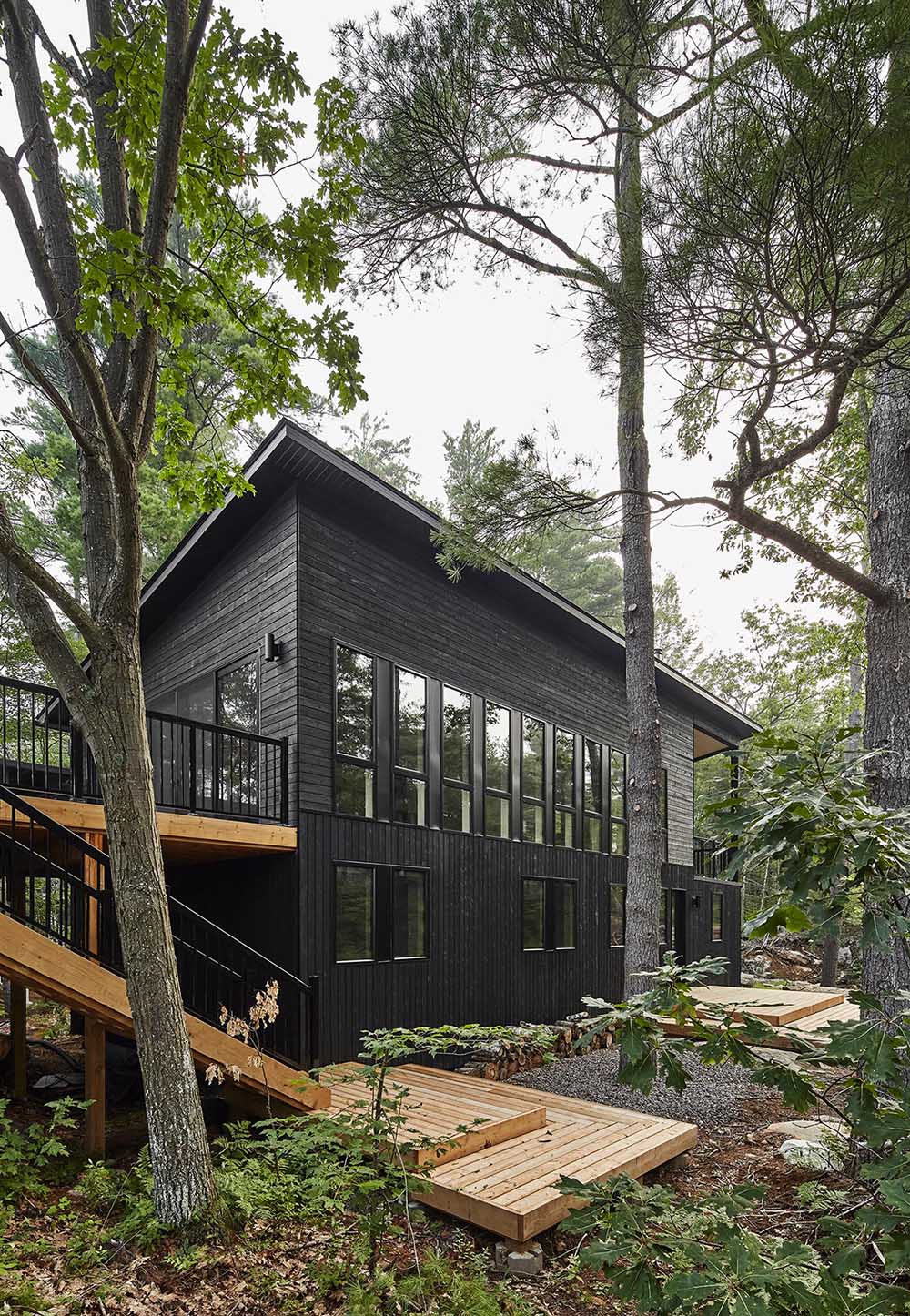 A modern cottage with black wood siding and matching black window frames.