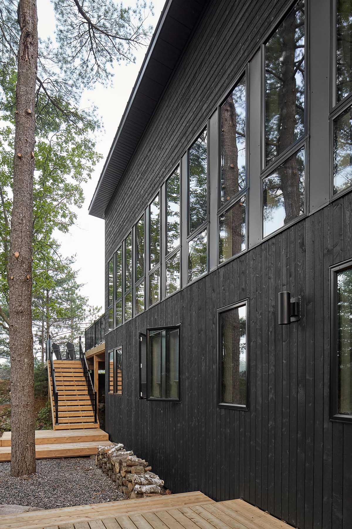 A modern cottage with black wood siding and matching black window frames.