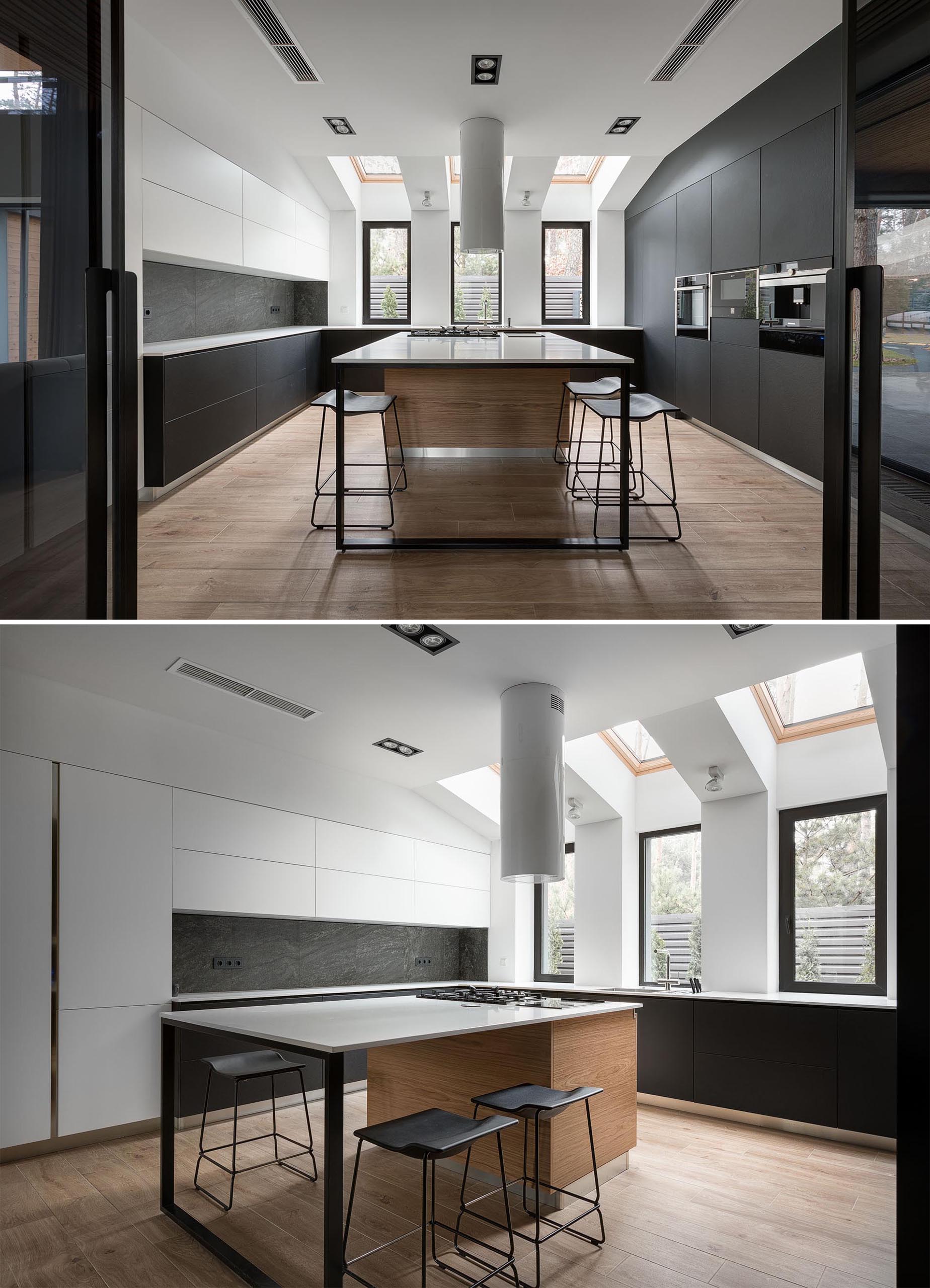 This modern kitchen, which can be opened or closed off to the dining room, includes minimalist, hardware free matte black and white cabinets, as well as an island with a cooktop, and skylights.