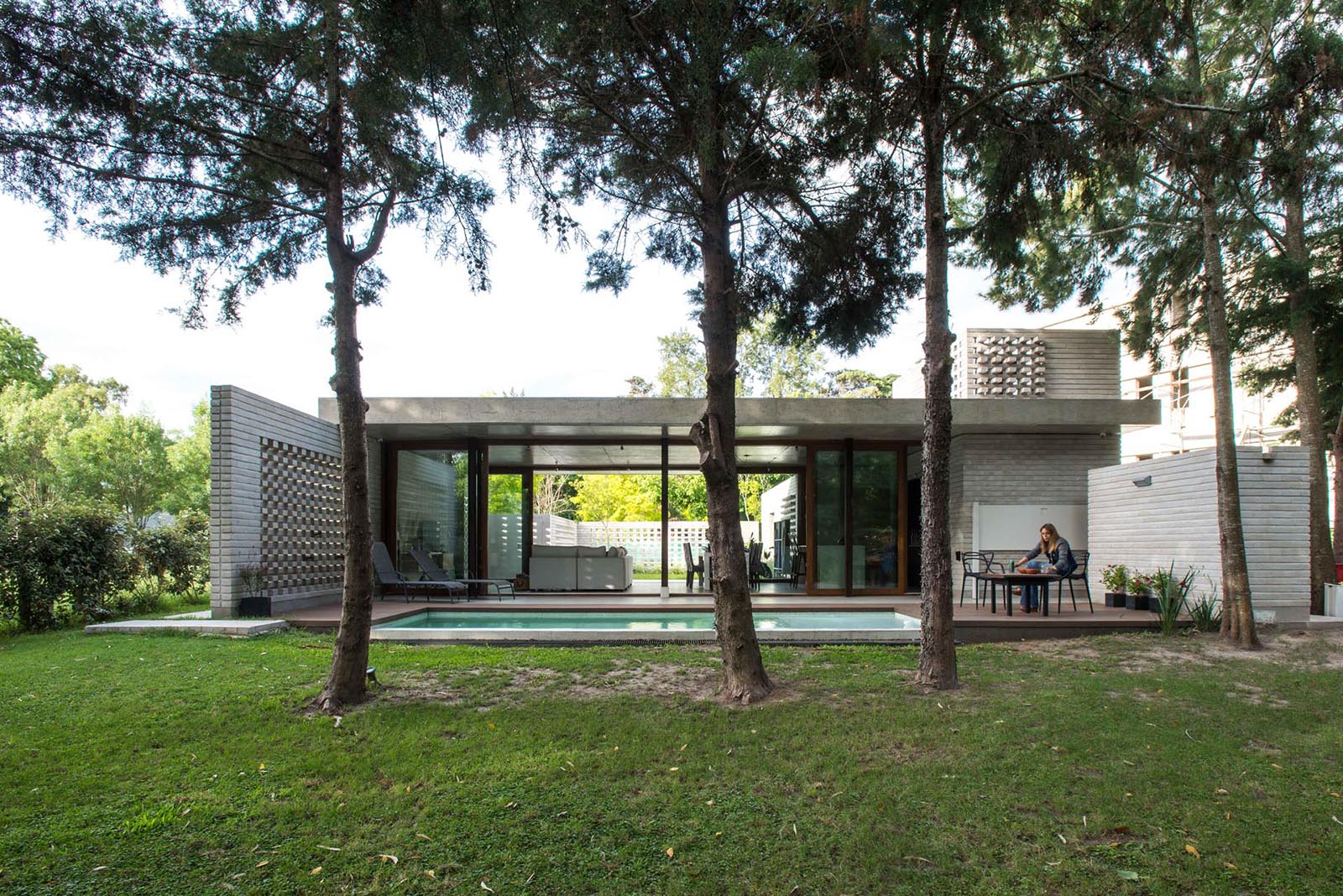 A modern concrete home with a swimming pool and glass walls.