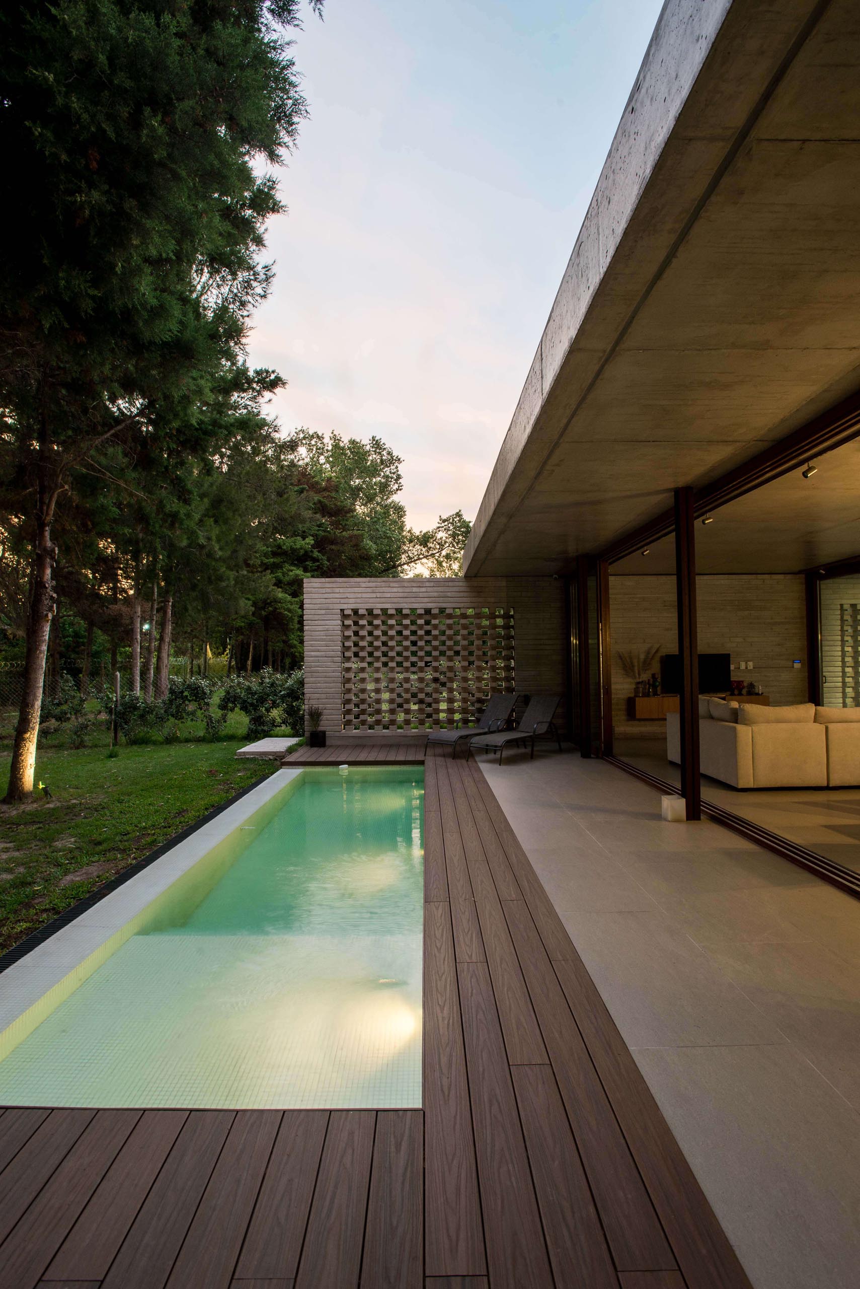 A modern concrete home with sliding glass walls and a swimming pool.