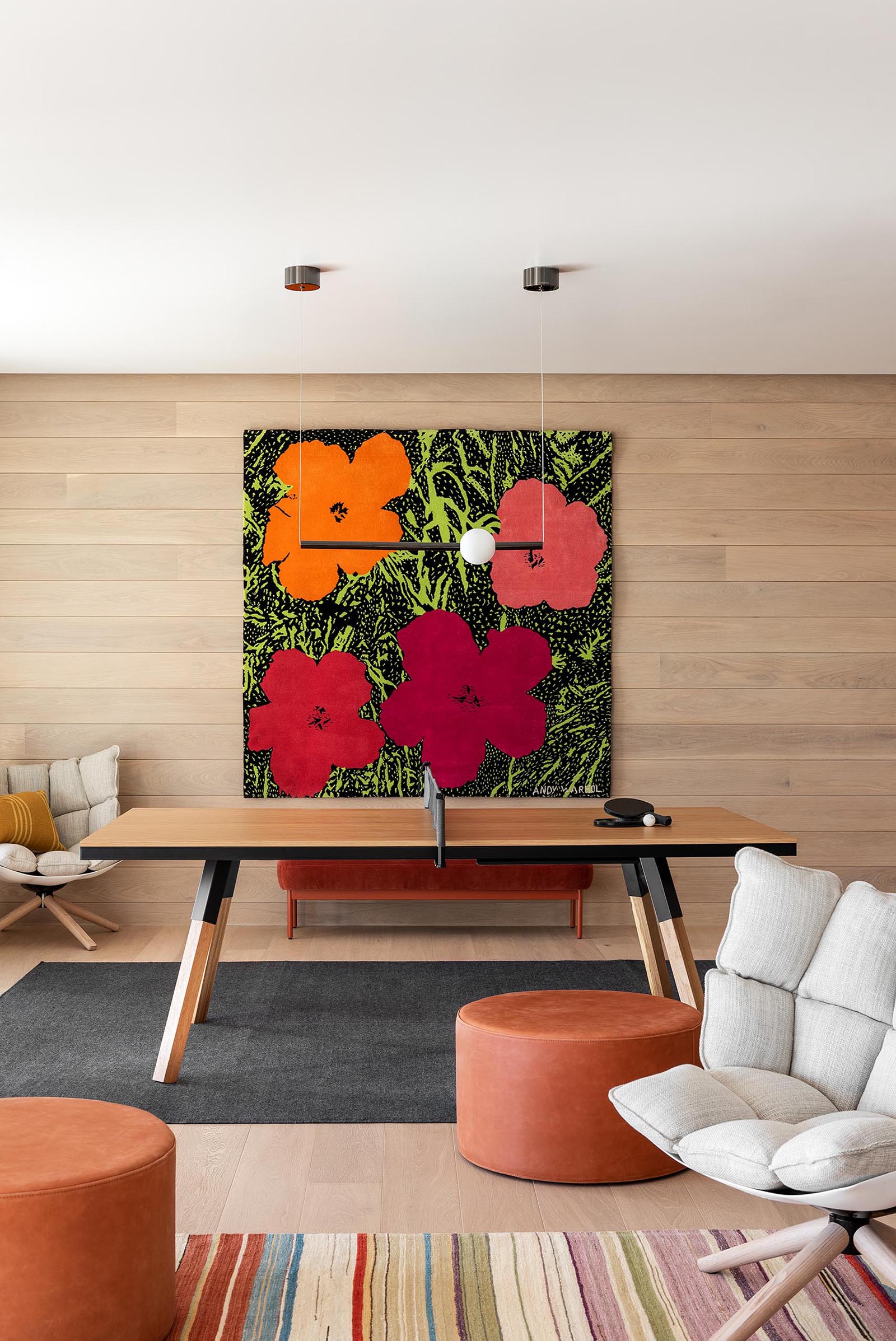 A modern games room with a wood accent wall adorned with a colorful floral art print.