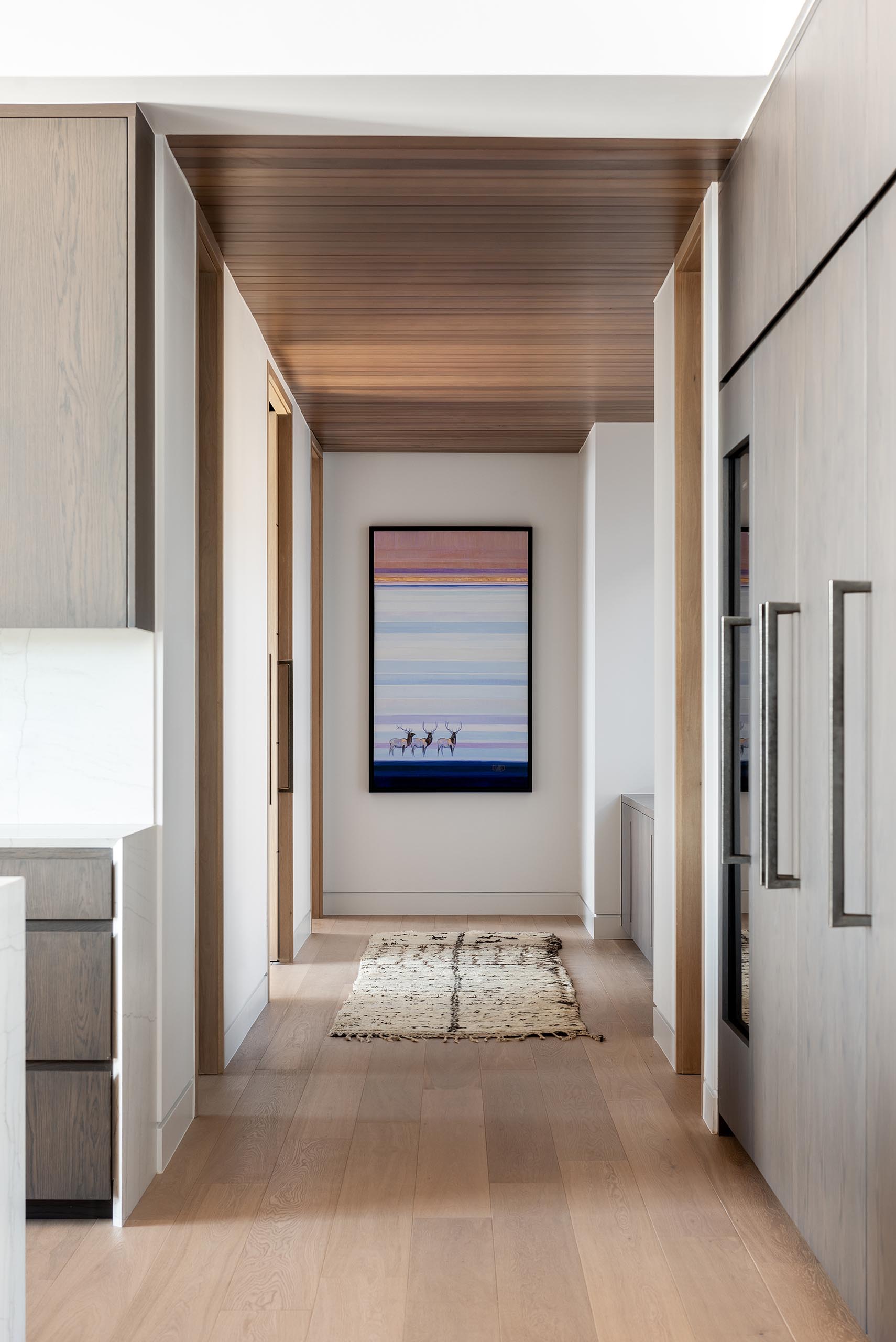 In this modern hallway, the wood ceiling and wood floors add warmth to the interior.