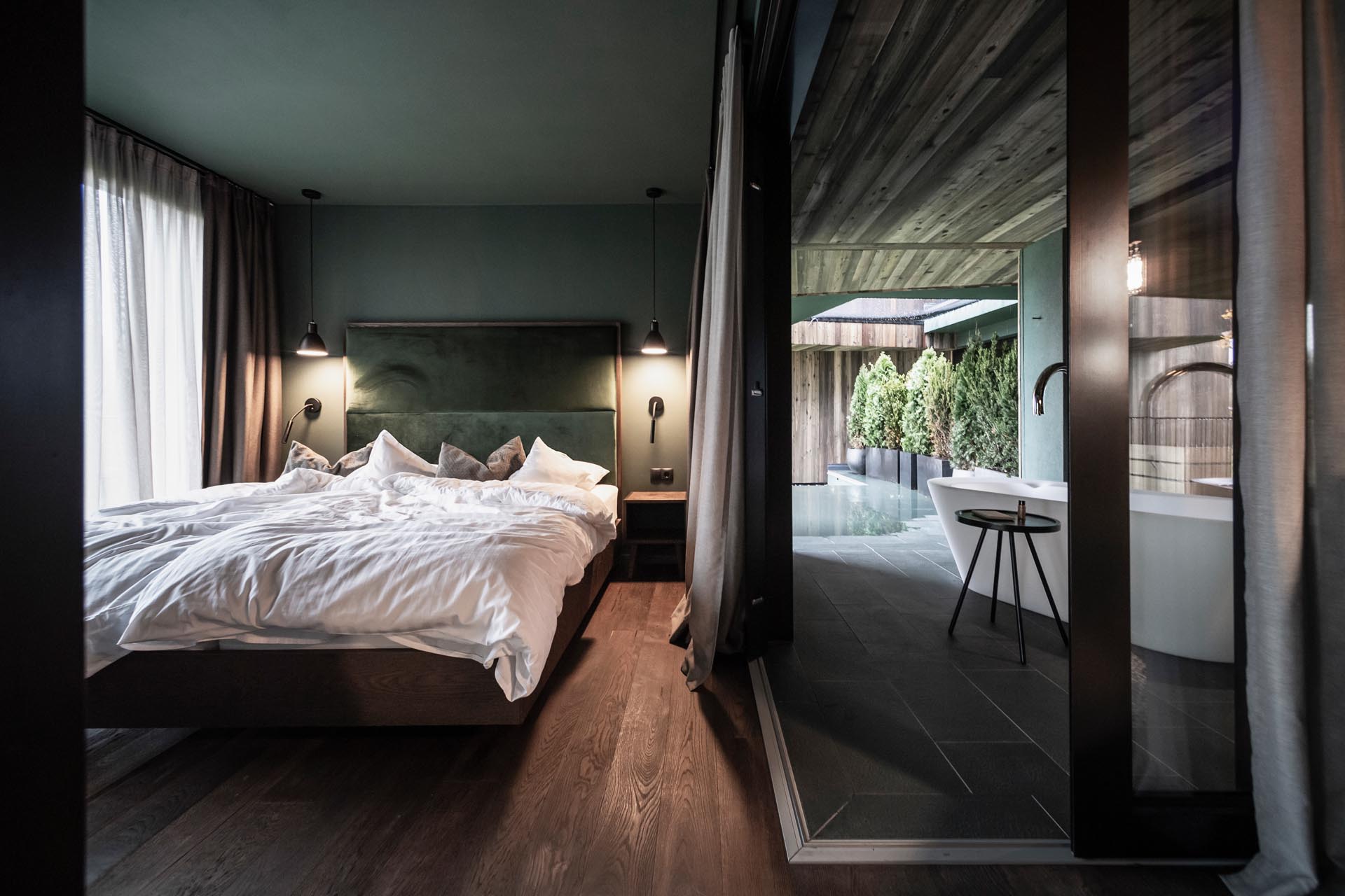 A modern hotel room a glass walled bedroom and outdoor bathtubs.