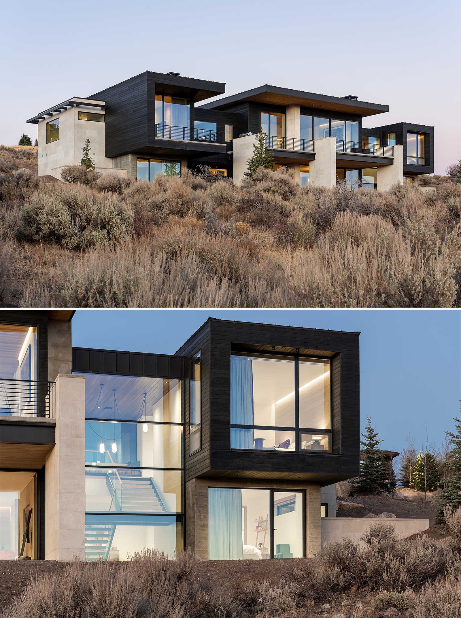 The exterior of this home includes exposed concrete and black siding, while a glass front door gives a glimpse of the interior.