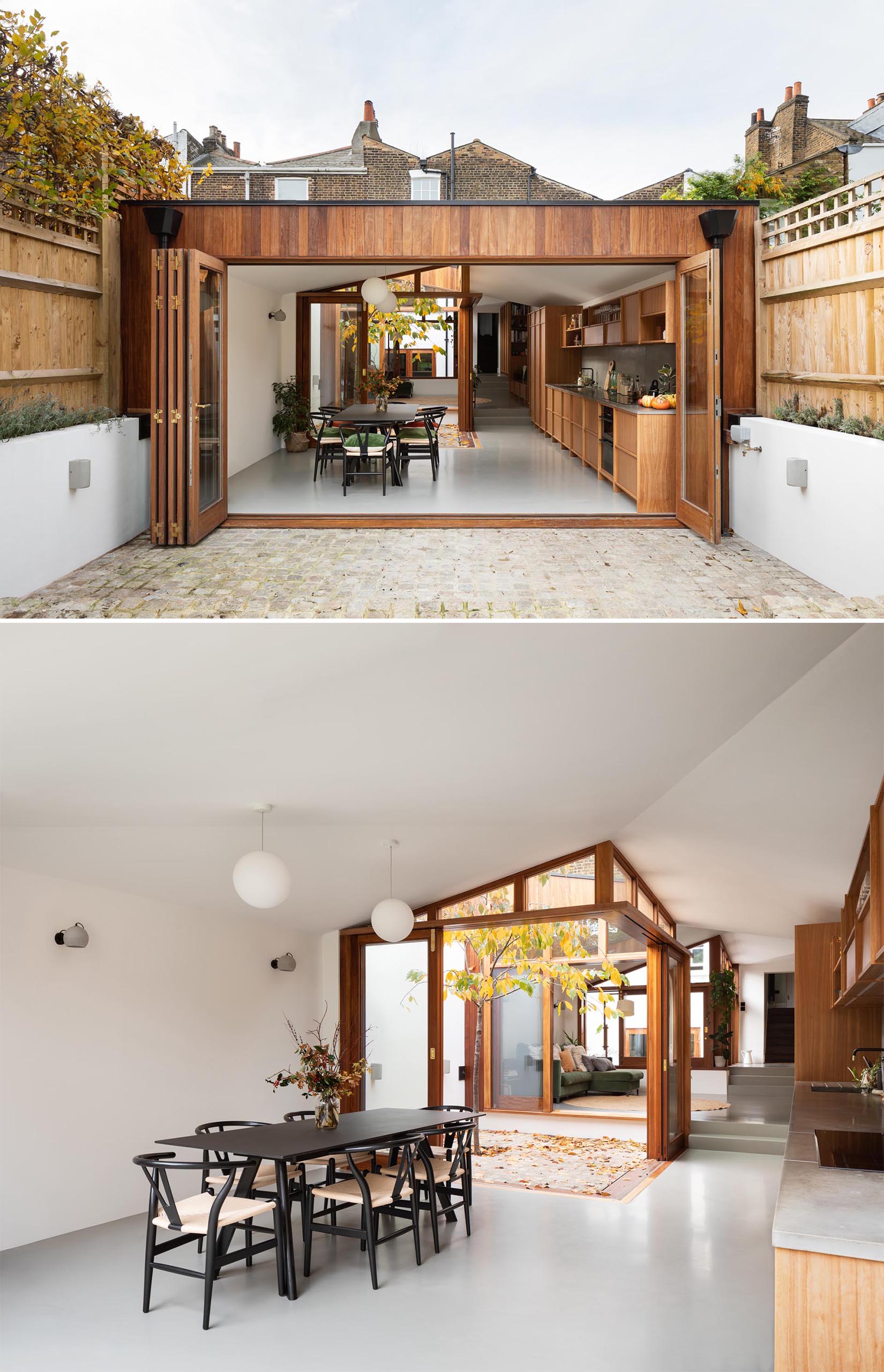 This new extension, which has folding glass doors, has a dining room furnished with a black table and chairs, contrasting the white walls and gray floors.