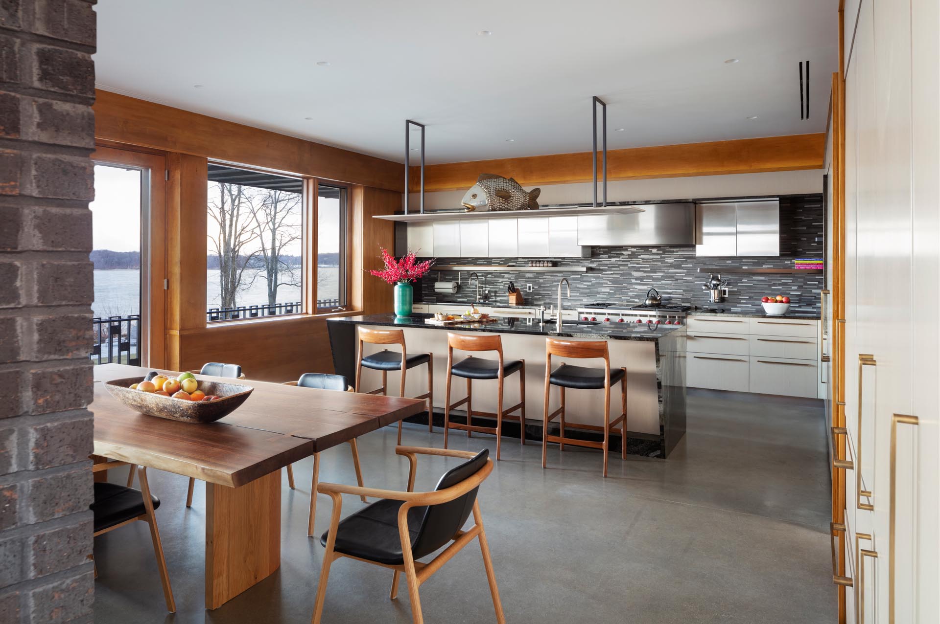 A modern kitchen with stainless steel cabinets, an island, and a dining area.