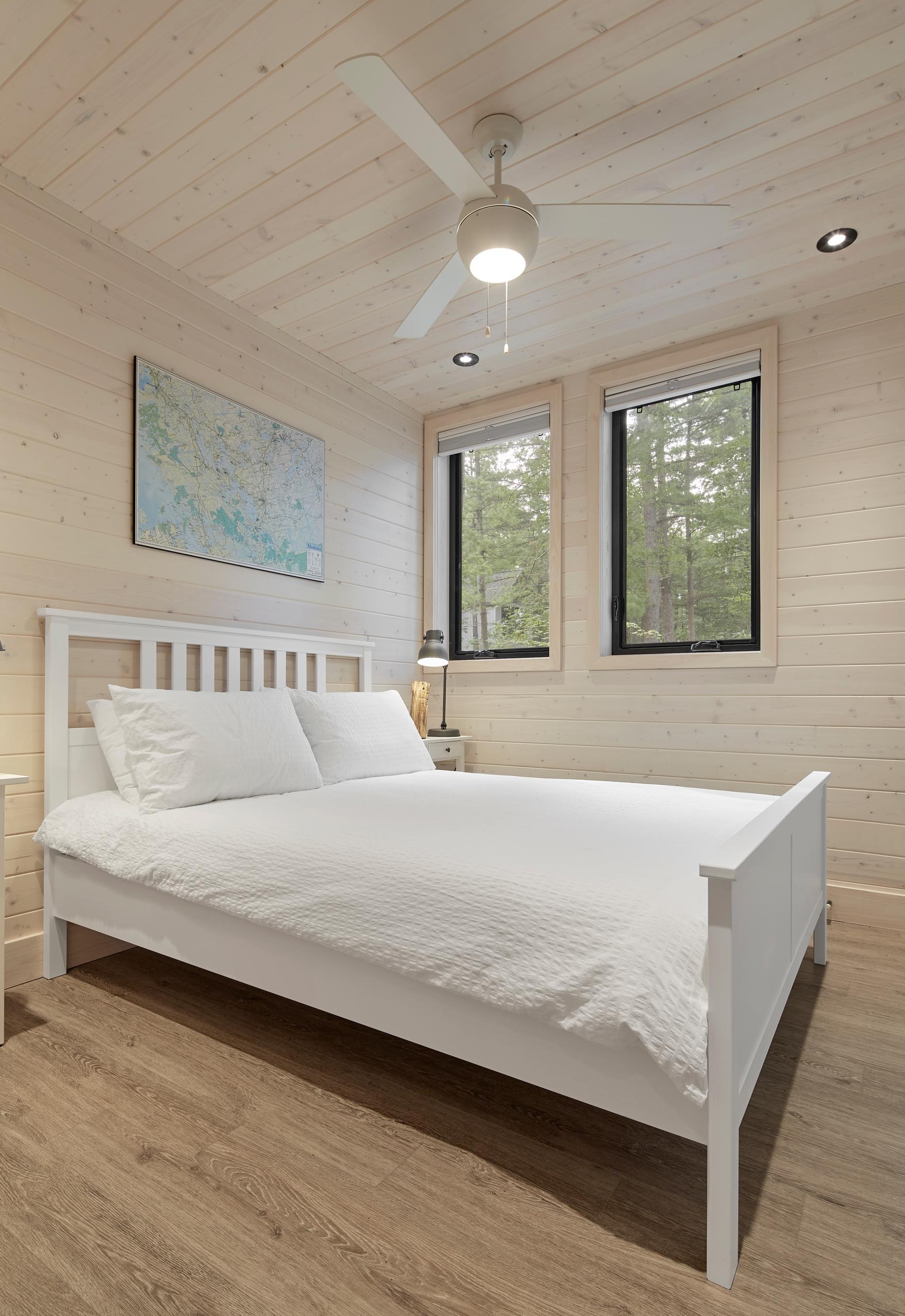A modern cottage bedroom with light wood walls and ceiling.