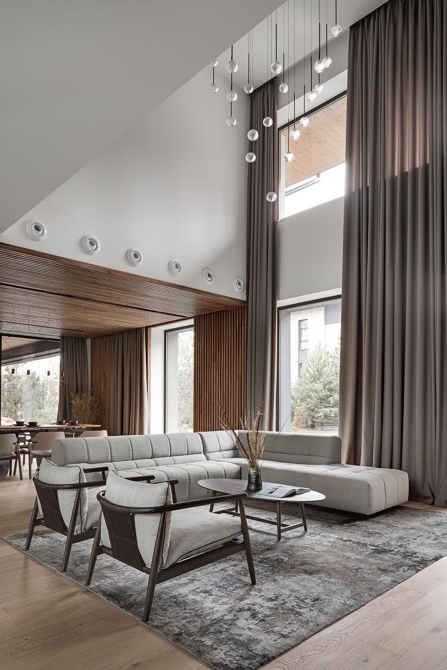 In this modern living room, there's a double height ceiling with a sculptural light installation.