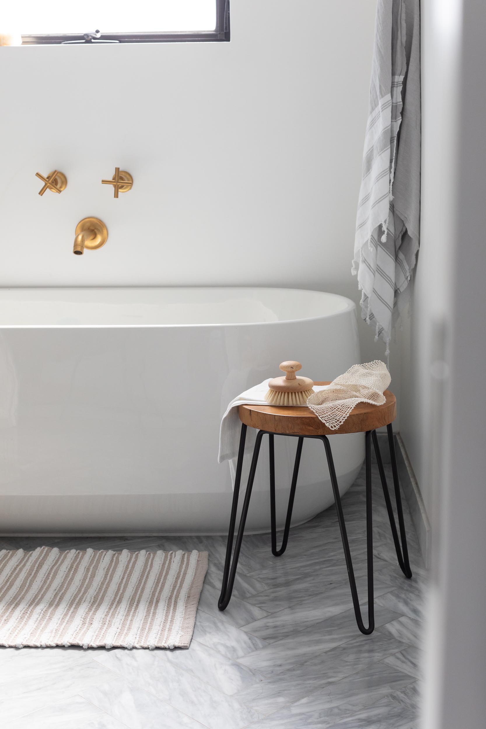 In this modern en-suite bathroom, there's a freestanding white bathtub, a walk-in shower, and a wood vanity with a waterfall countertop.