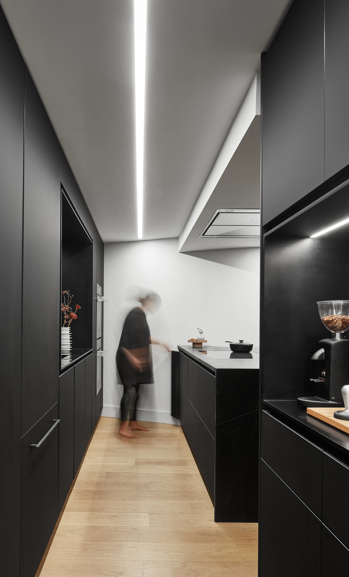 A modern matte black kitchen with hardware free cabinets, a large island, and a coffee station.