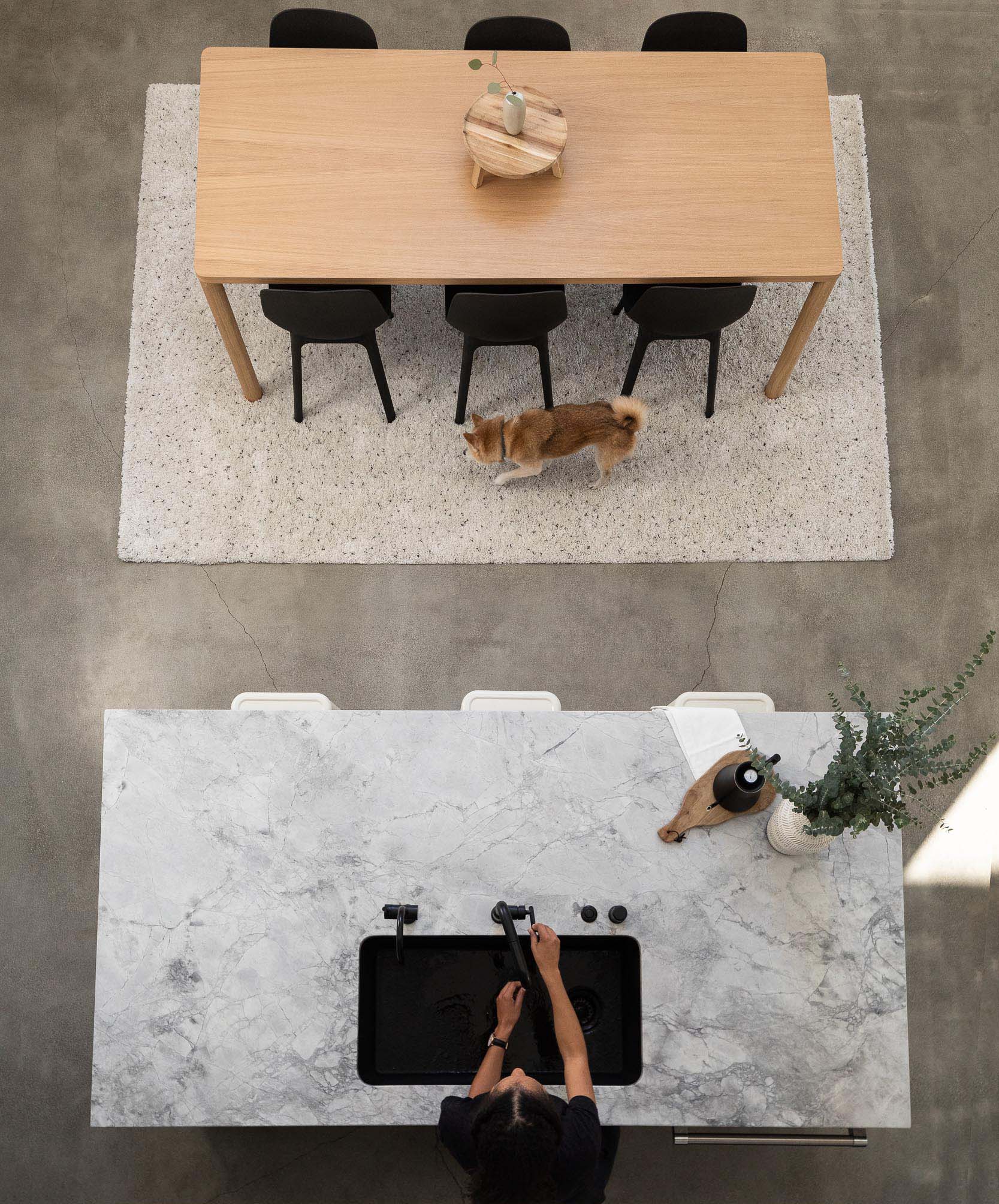 This modern home interior has the dining room next to the kitchen island, which was designed with with room for seating, while the kitchen has matte black lower cabinets and light wood upper cabinets.