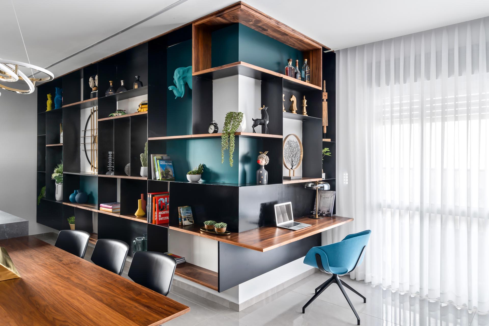 One of the key design elements in this apartment is the inclusion of an entire wall that's filled with steel and wood shelving, and has pop of turquoise adding a colorful accent to the open plan interior.