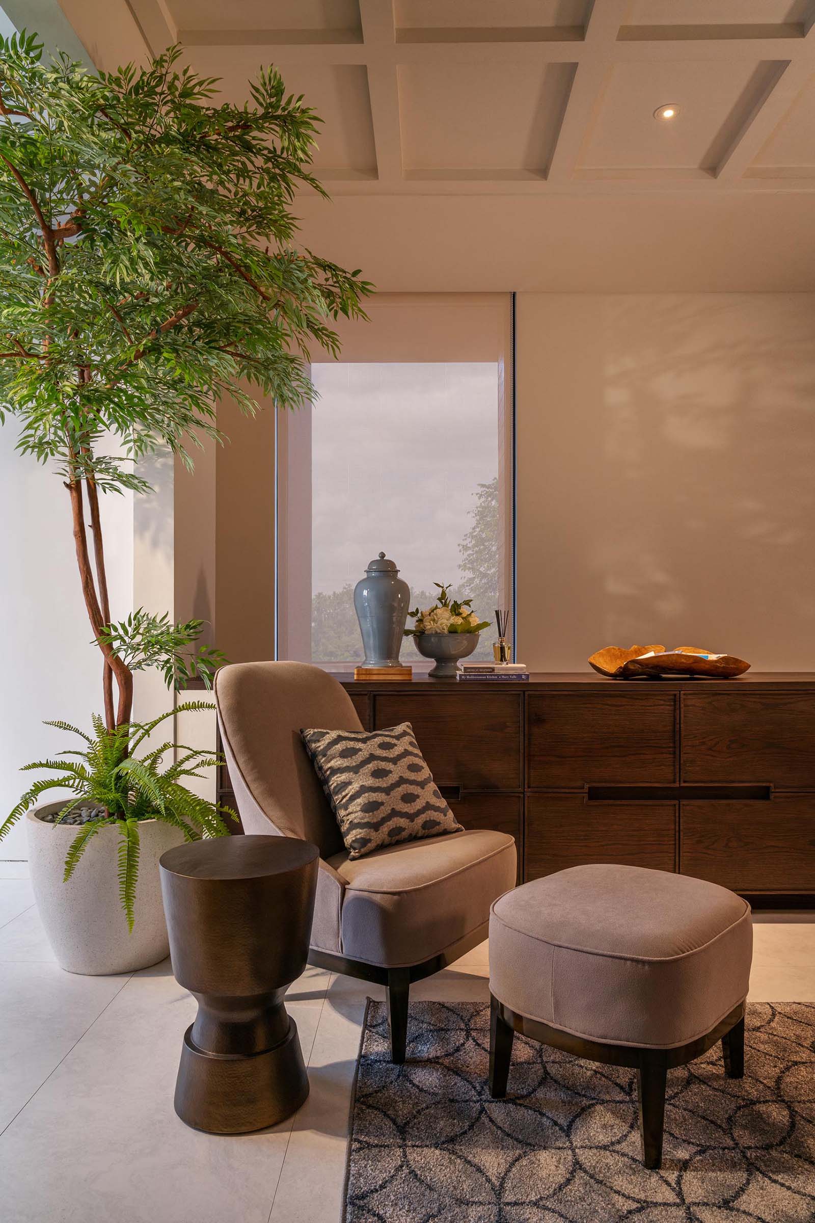 A sitting room with a wood sideboard and a comfortable chair with an ottoman.