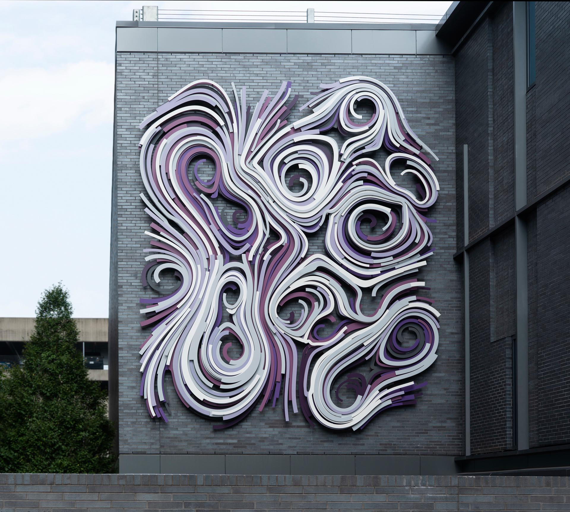 A modern large scale art piece on the side of a building.