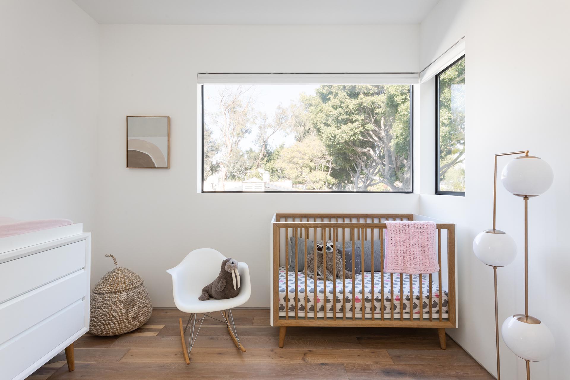 A nursery with large windows and simple yet modern furnishings.