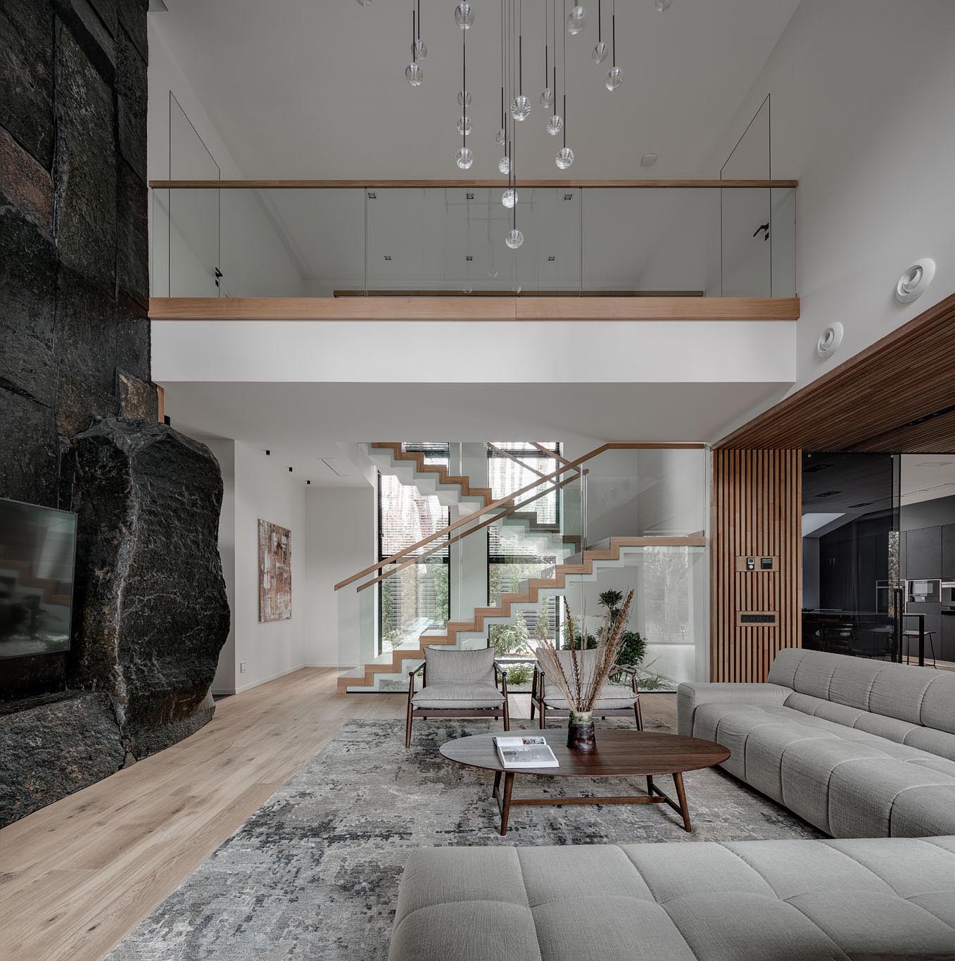 These modern stairs that connect the various levels of the home are made of concrete, wood, and glass. Underneath the stairs, live indoor plants and rocks have been used to create a small garden, bringing the outdoors in.