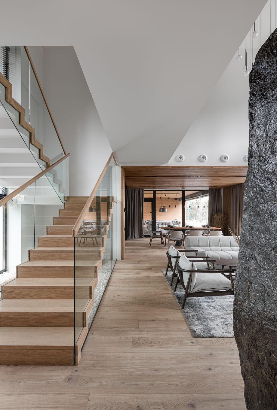 These modern stairs that connect the various levels of the home are made of concrete, wood, and glass. Underneath the stairs, live indoor plants and rocks have been used to create a small garden, bringing the outdoors in.