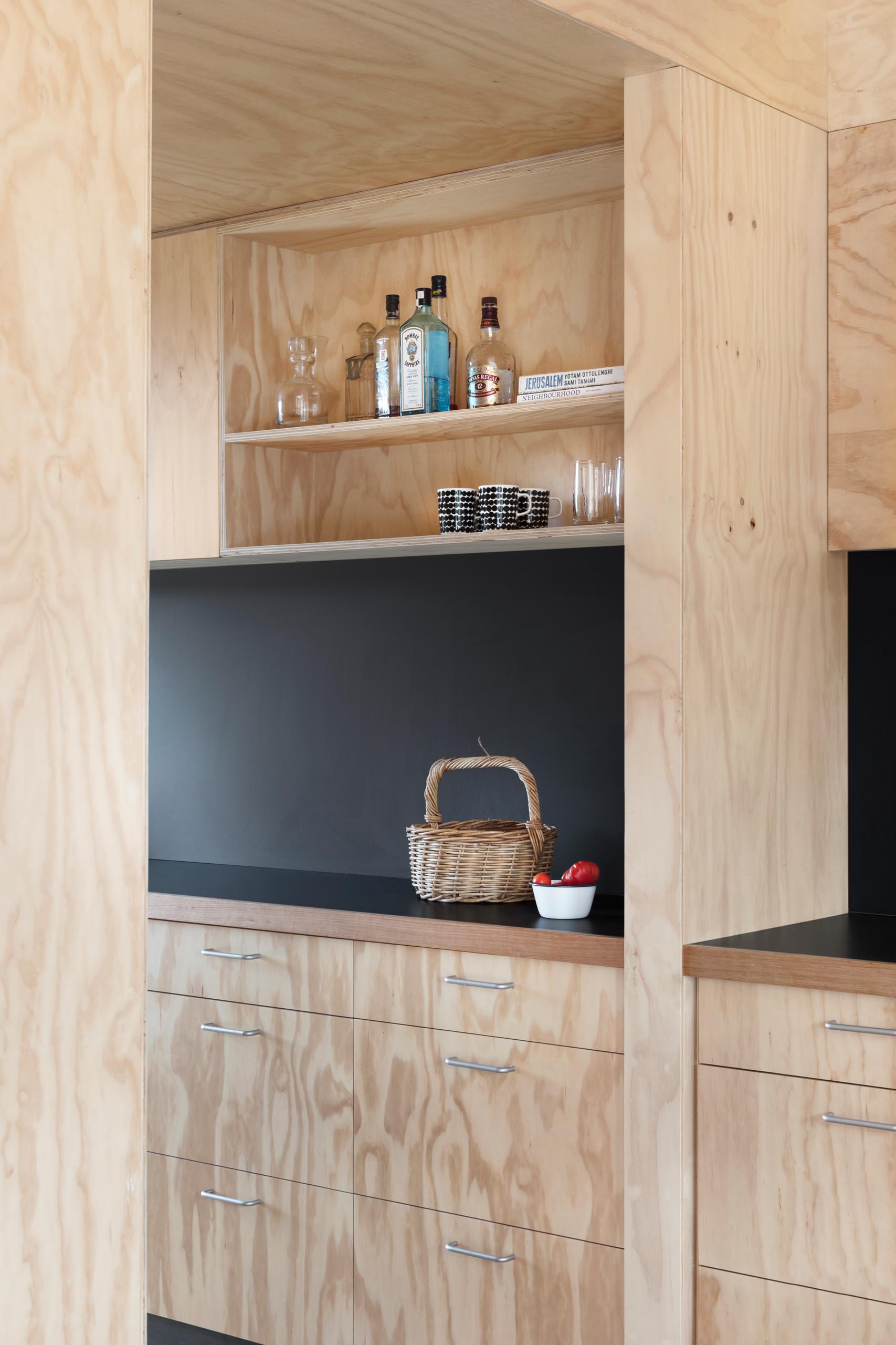 A modern plywood kitchen with a matte black countertop and backsplash.