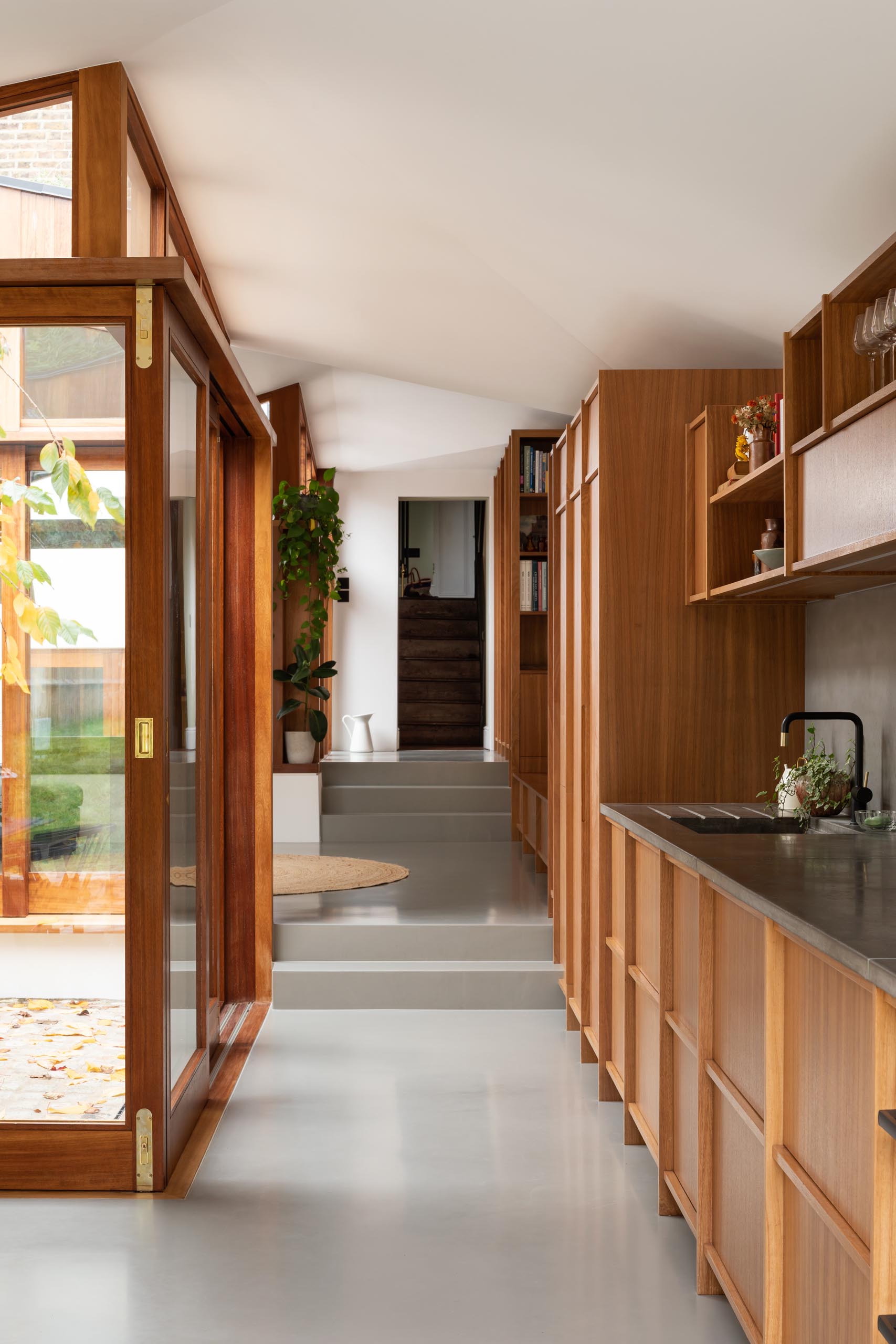 A linear wood kitchen with hardware free cabinets and a dark gray backsplash.